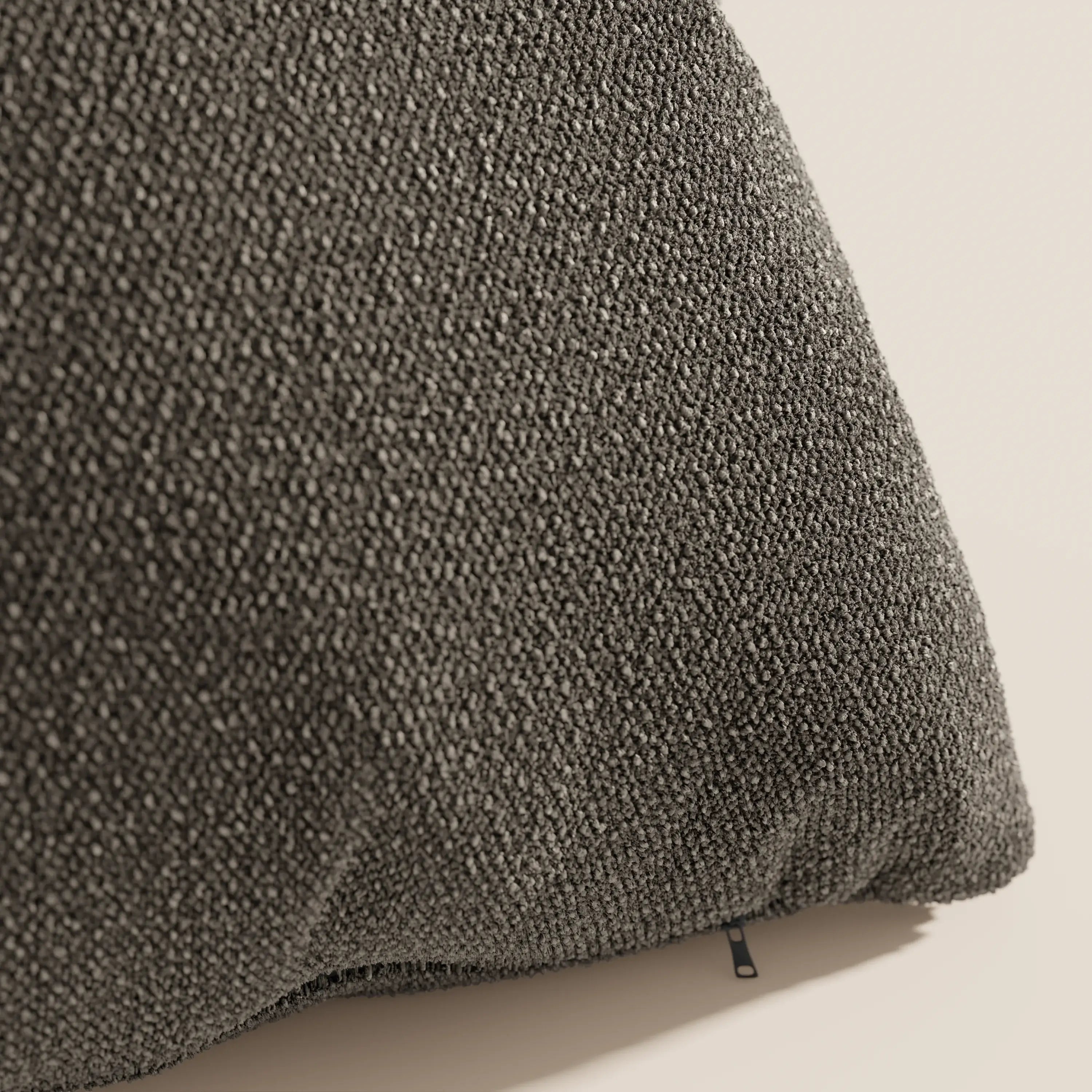 Primo piano del cuscino Lambada grigio scuro di Divani.Store, realizzato in fresco tessuto naturale simil-cotone (T33) lavabile e impermeabile, caratterizzato da una finitura a ciottoli e arricchito da una piccola etichetta in tessuto nero.