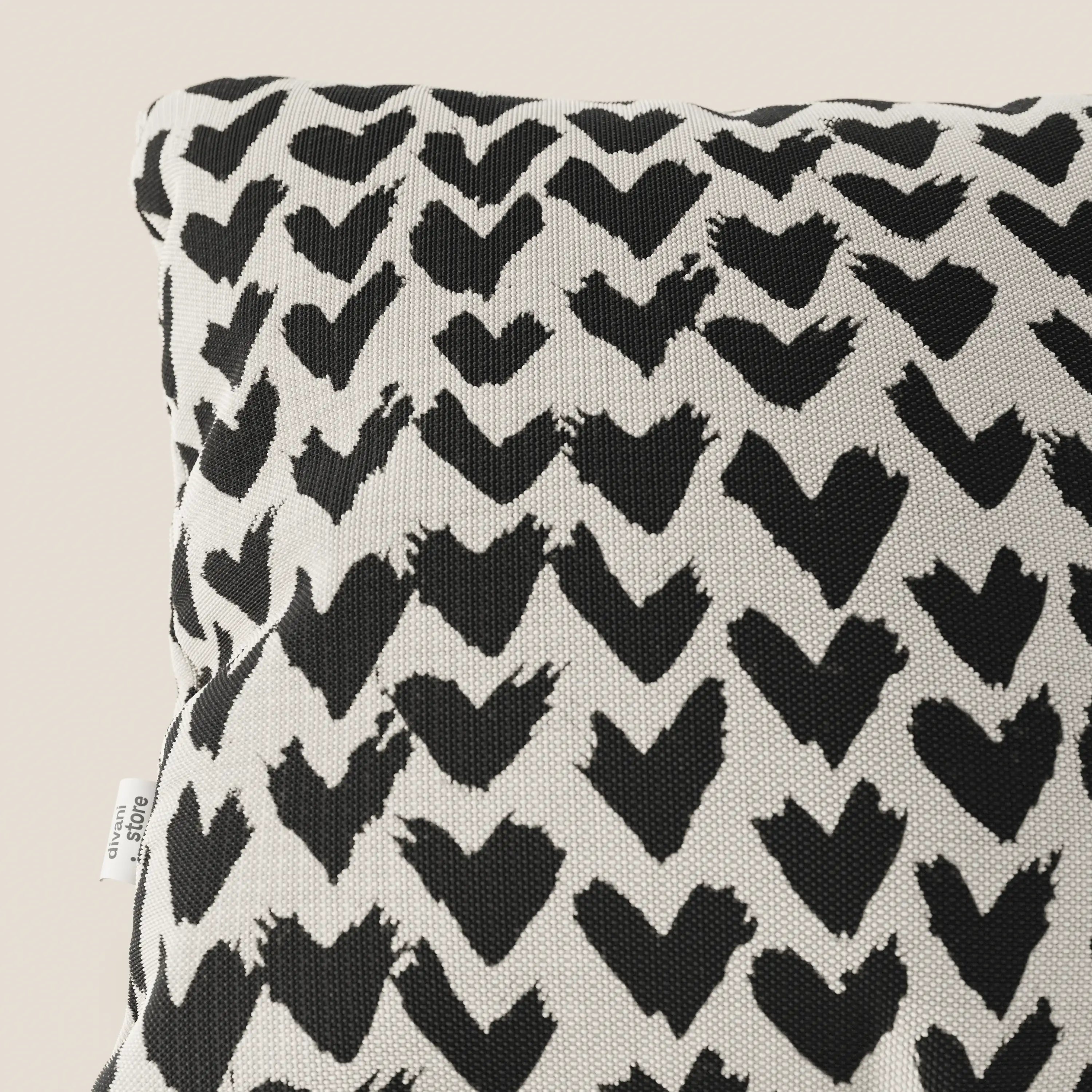 Primo piano dei cuscini geometrici Arrow di Divani.Store, realizzati in tessuto nero idrorepellente e disponibili in vari colori. Una piccola etichetta bianca sul bordo indica "cotone 100%".