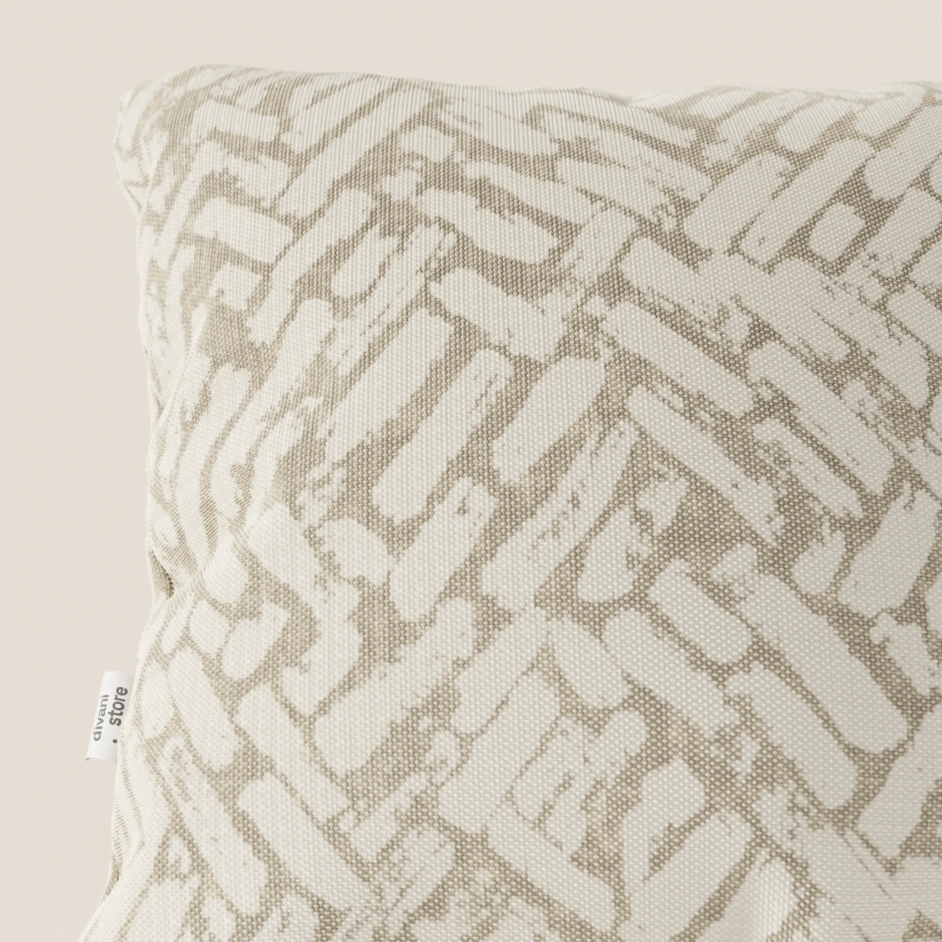Primo piano del cuscino geometrico Brick di Divani.Store, presentato in tessuto idrorepellente beige con un motivo ispirato ai mattoni e una piccola etichetta bianca. Il suo design moderno spicca su uno sfondo semplice e chiaro.