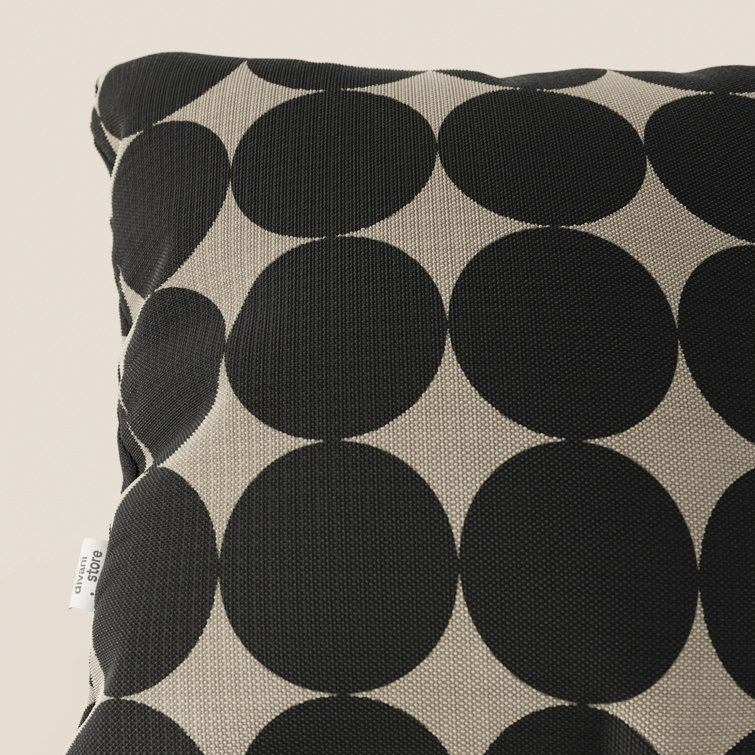 Un primo piano dei cuscini geometrici Dot di Divani.Store, caratterizzati da grandi cerchi neri sovrapposti su tessuto tortora idrorepellente, con una piccola etichetta bianca cucita nella cucitura laterale.
