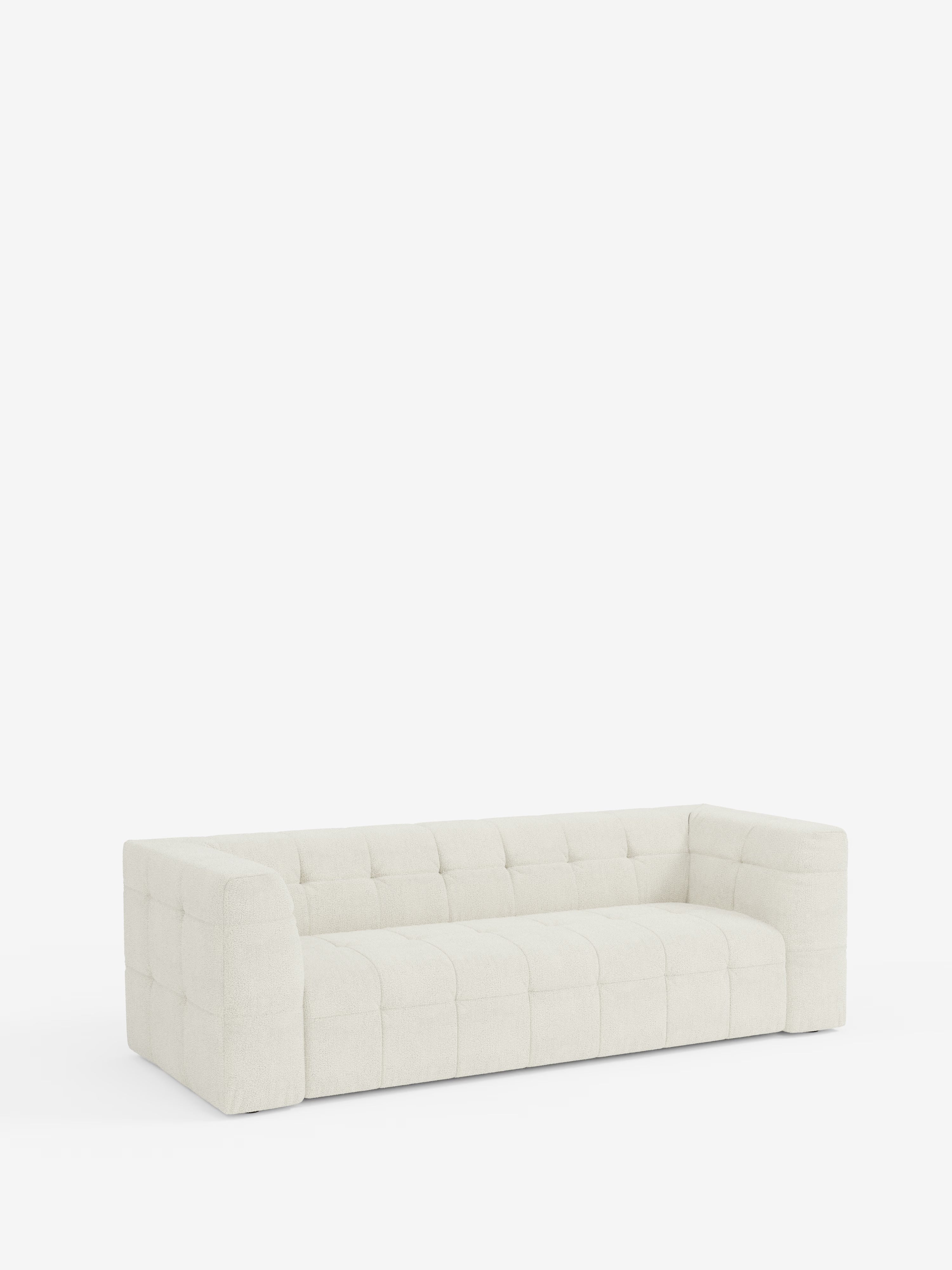Un divano modulare contemporaneo e dal profilo basso, il modello Mosaic Divano a 3 e 4 posti in bouclé di Divani.Store, caratterizzato da braccioli squadrati e spessi e da uno schienale in tessuto T21 beige chiaro, facile da pulire. Il rivestimento è capitonné, creando un motivo a griglia morbido che aggiunge consistenza e fascino visivo. Su uno sfondo bianco a tinta unita, le linee pulite e il design modulare del divano risaltano in perfetto stile minimalista.