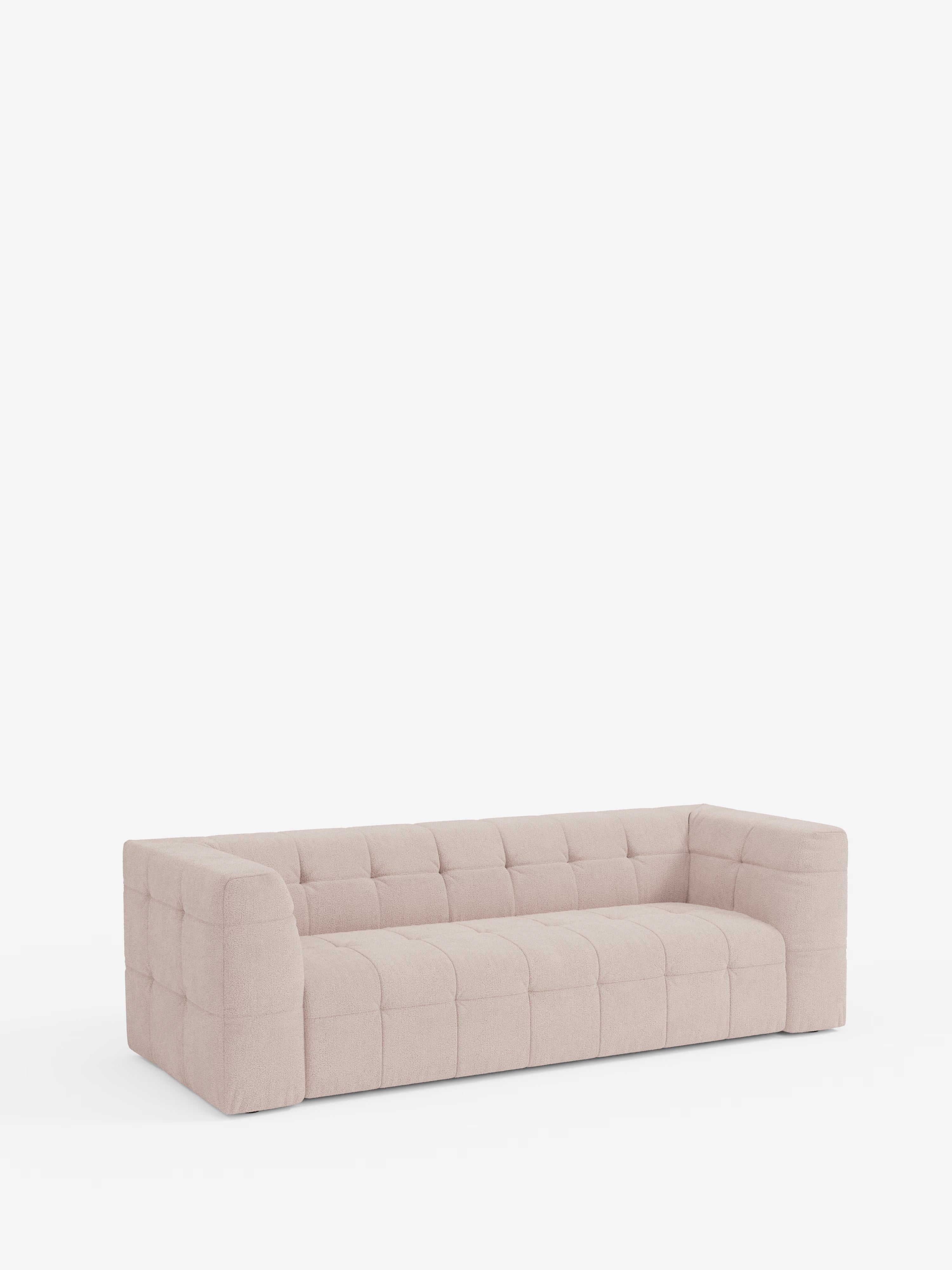 Il divano modulare Mosaic a 3 e 4 posti in bouclé: capitonné e design in tessuto antimacchia T21 di Divani.Store, un moderno divano modulare beige caratterizzato da rivestimento capitonné a quadri, ampi braccioli e schienale basso, si staglia su uno sfondo bianco a tinta unita. La sua silhouette squadrata e la superficie morbida e imbottita esaltano il comfort e lo stile contemporanei.