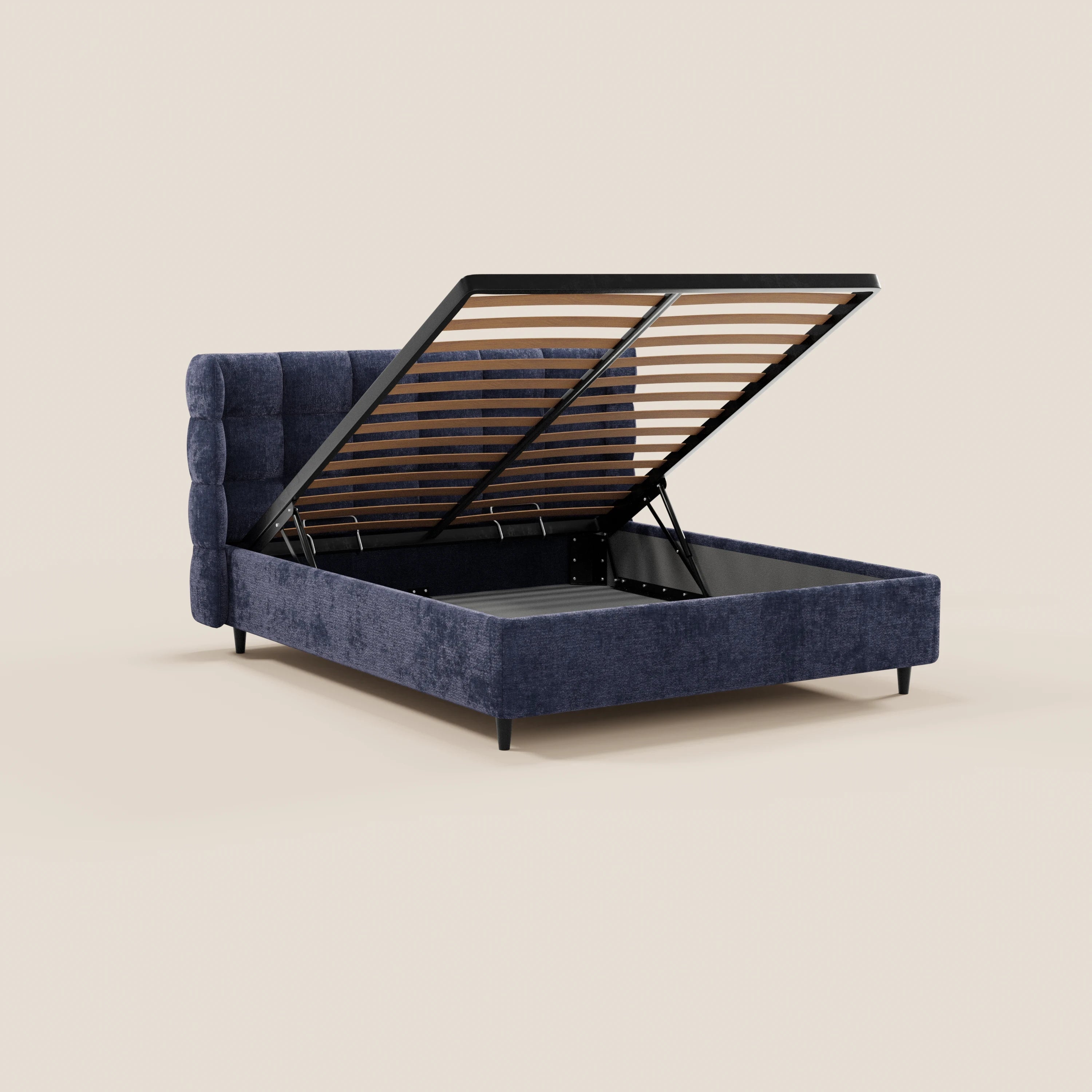 Il letto imbottito RAGNAR di Letti.store è caratterizzato da un tessuto blu certificato Oeko-Tex®, una testiera capitonné avvolgente, gambe nere e una base sollevabile che rivela un ampio vano contenitore con barre metalliche e doghe. Sfondo: beige chiaro a tinta unita.