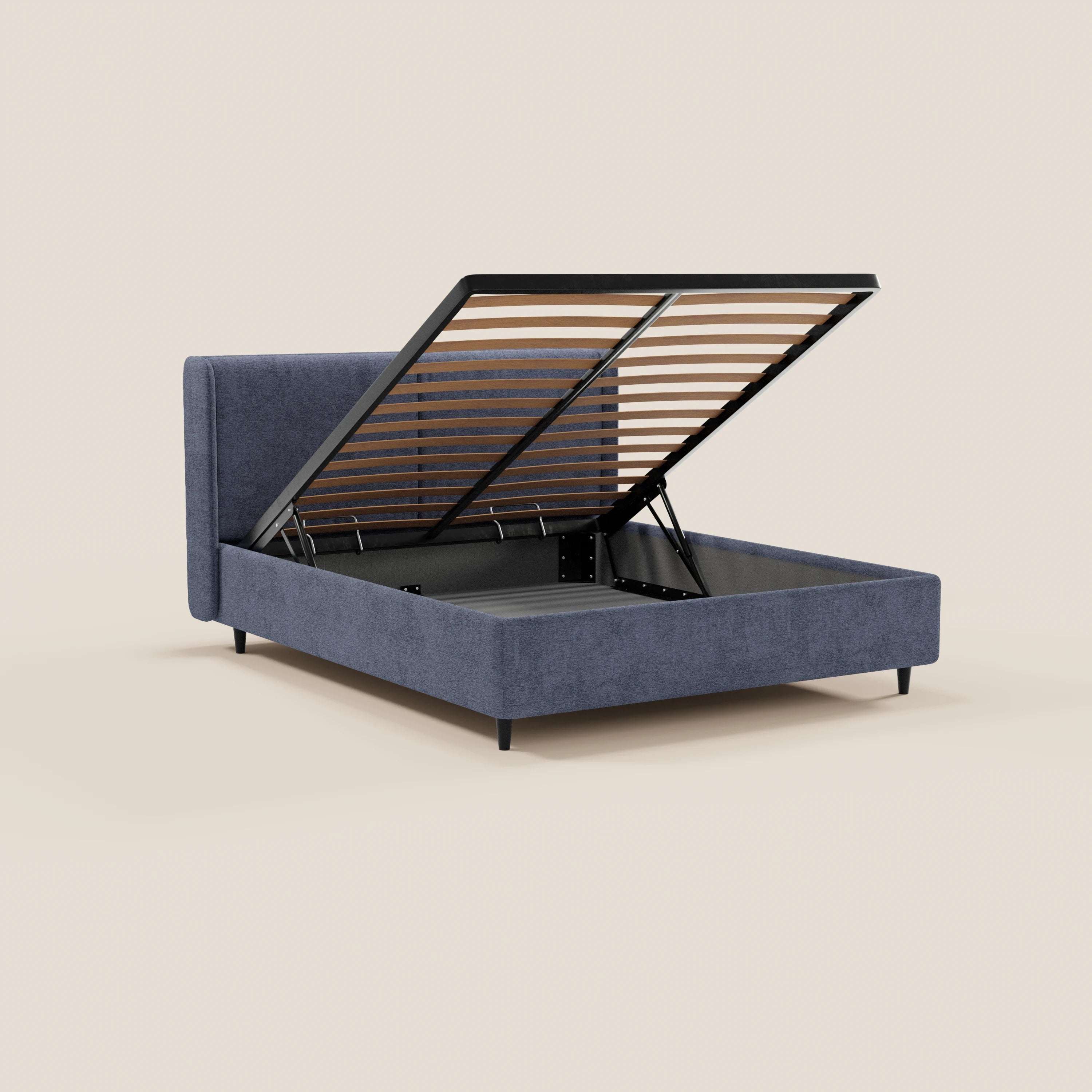 Il letto di design VALKIRIA di Letti.store, realizzato in tessuto grigio scuro certificato Oeko-Tex® con 2 cuscini imbottiti e una testiera avvolgente, è dotato di una rete a doghe sollevabile che offre un ampio spazio contenitivo. Nella foto è raffigurato su gambe corte nere su uno sfondo beige.