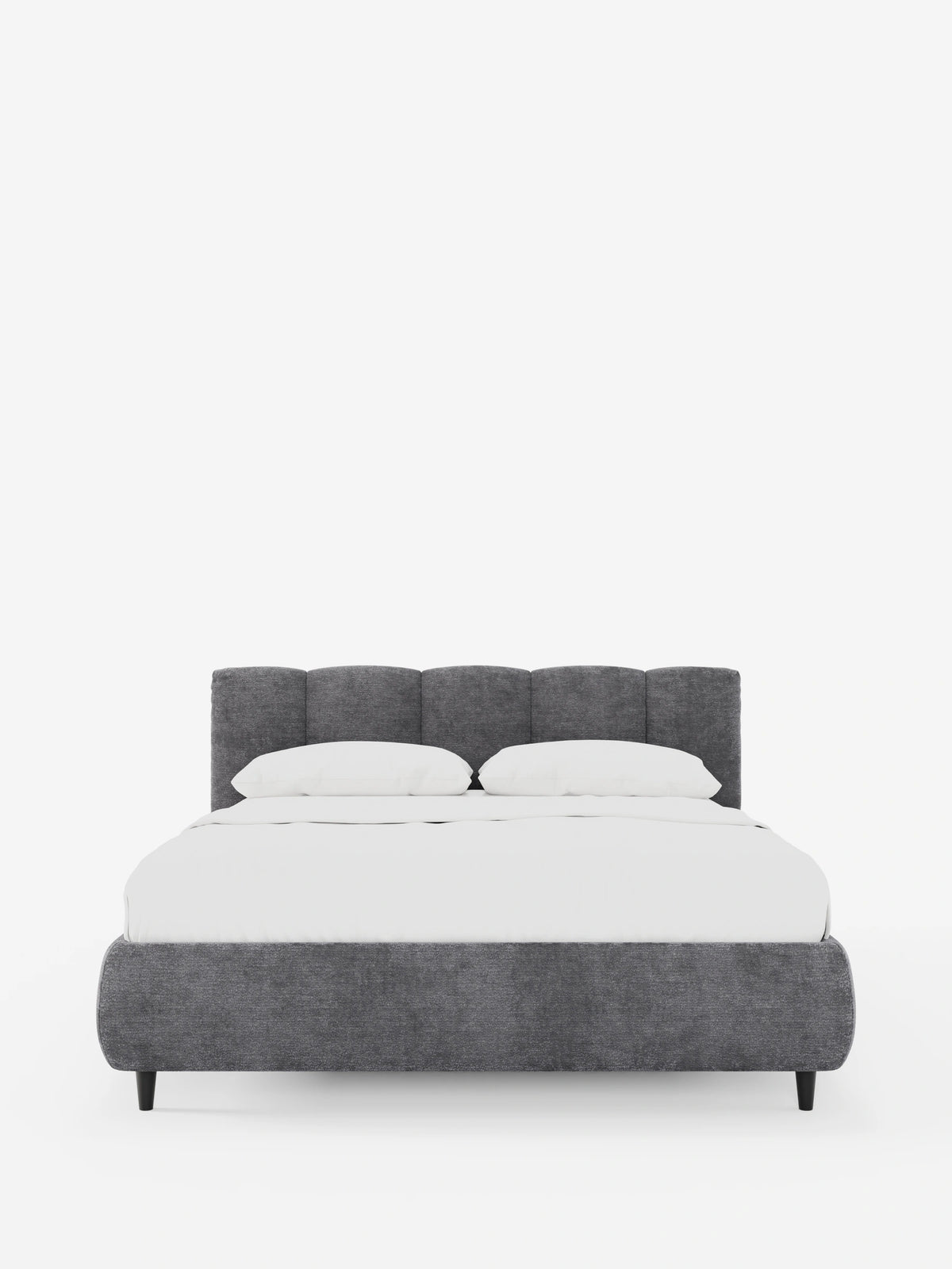 Il letto imbottito ARKAM con contenitore e testiera a lavorazione verticale è un letto imbottito di colore grigio scuro con dettagli a pannelli verticali, biancheria da letto di un bianco brillante e quattro gambe scure e affusolate che si stagliano su uno sfondo bianco.