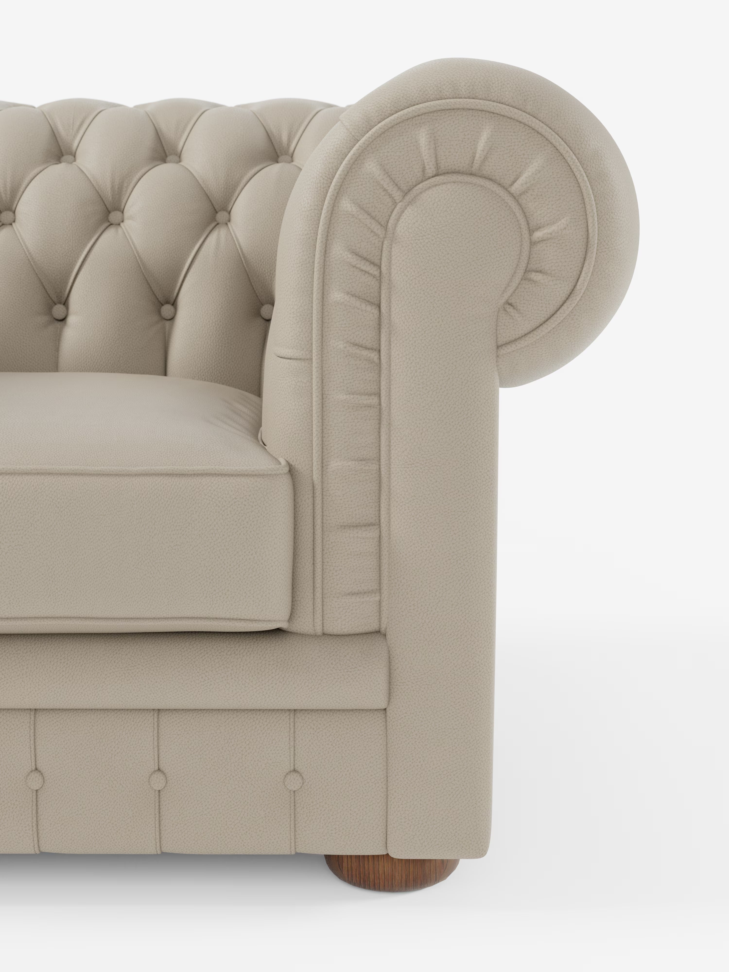 Primo piano del bracciolo destro della poltrona Chester in vera pelle spessorata con capitonné artigianale di Divani.Store, che mette in risalto il design arrotondato a voluta, la classica trapuntatura a bottoni che richiama lo stile delle poltrone capitonné e una gamba in legno a vista. Su uno sfondo bianco a tinta unita, sono visibili solo una parte del cuscino di seduta e dello schienale del divano.