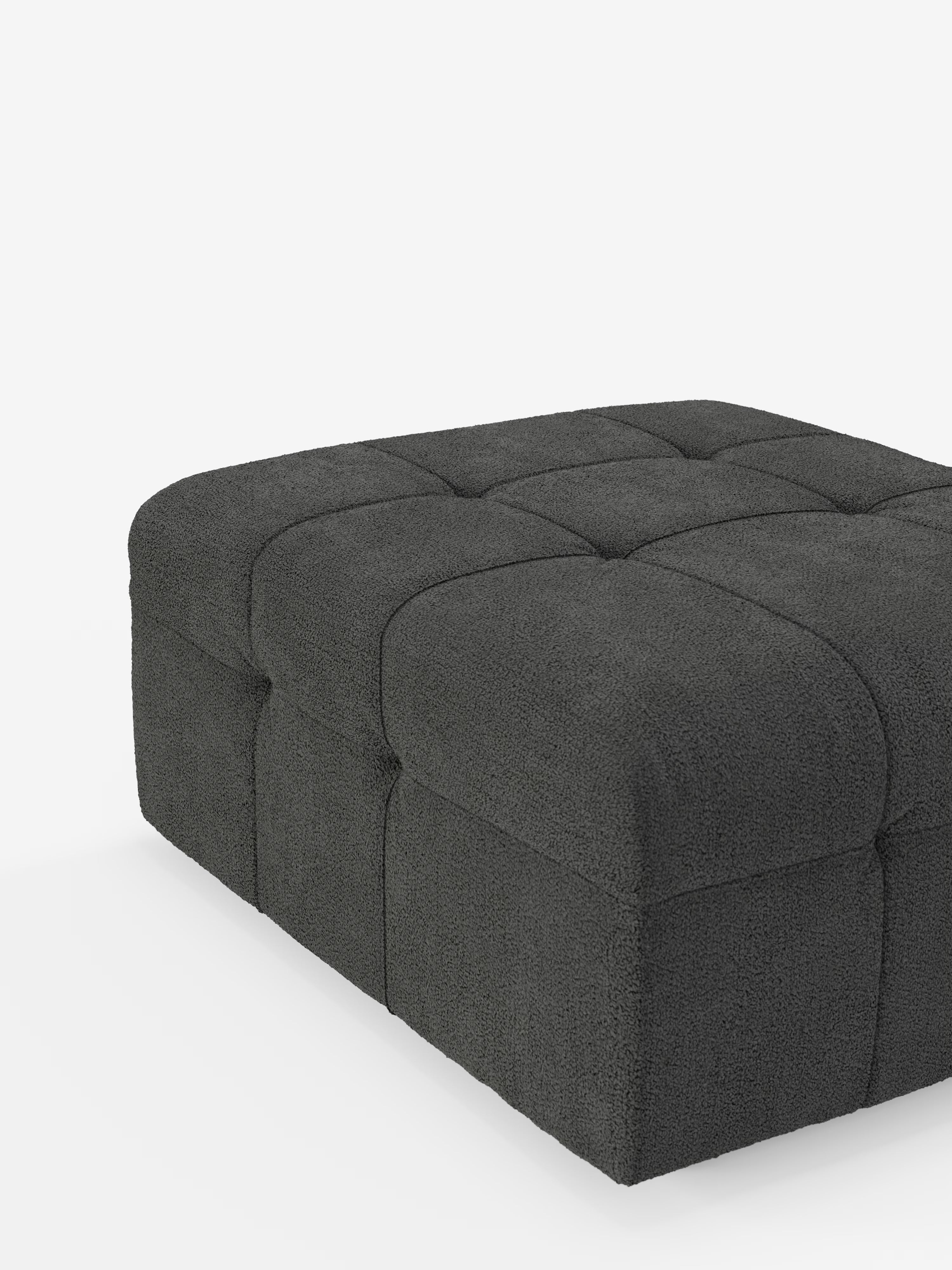Un grande pouf quadrato “Mosaic” e modulo in bouclé di Divani.Store, dalle dimensioni di 96x77 cm, è rivestito in tessuto T21 grigio scuro antimacchia, con una finitura morbida e testurizzata e un elegante motivo capitonné. La superficie è suddivisa in quadrati rialzati e imbottiti; il pouf è raffigurato su uno sfondo bianco a tinta unita.
