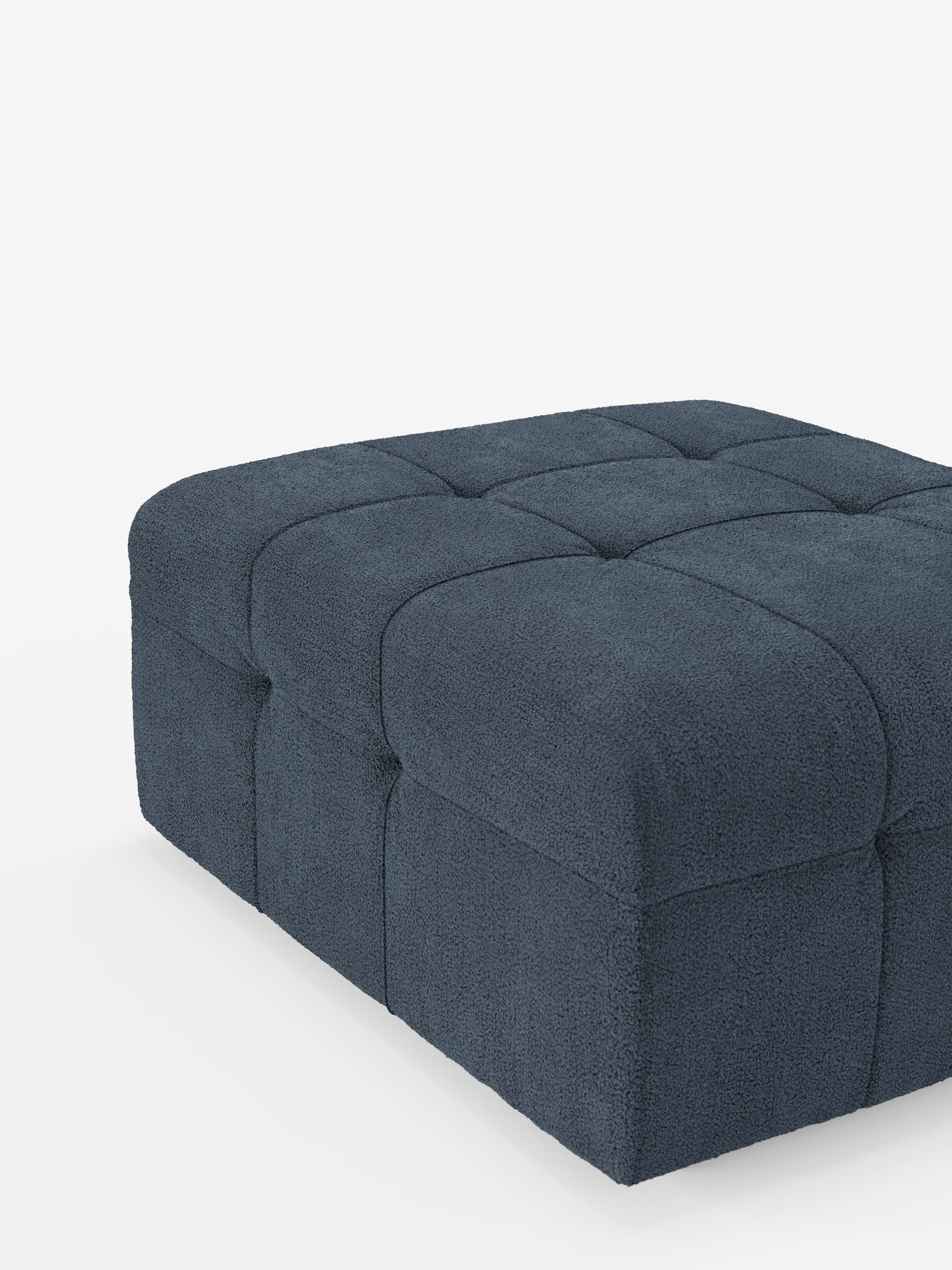 Un pouf contemporaneo di Divani.Store, il modello Mosaic in bouclé (96x77 cm), si distingue per l’elegante design capitonné rivestito in tessuto T21 antimacchia. Il tessuto bouclé blu scuro e la profonda trapuntatura a griglia si sposano perfettamente con la silhouette squadrata dai bordi delicatamente arrotondati, emanando un’eleganza raffinata sullo sfondo di un bianco brillante.