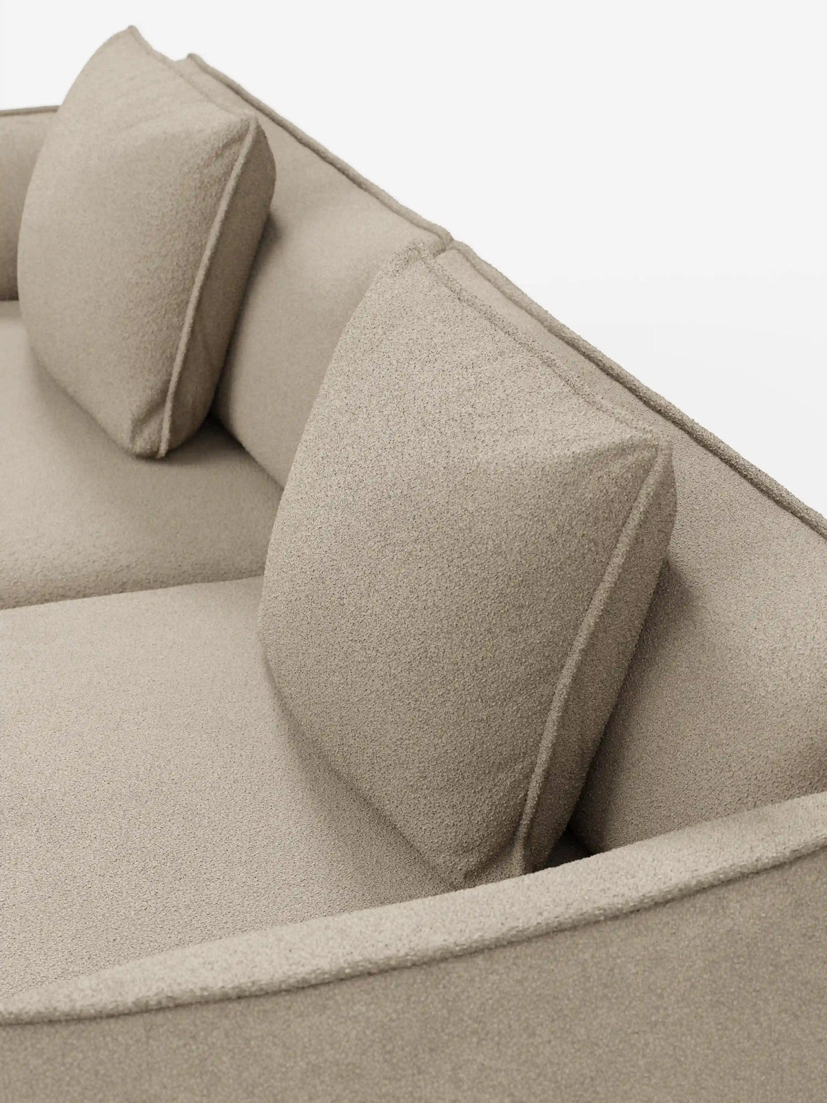 Primo piano del divano Nimbus a 3 posti, modulare e componibile da 250 cm di Divani.Store, rivestito in tessuto effetto cotone beige (t33), sfoderabile e antimacchia. Il divano modulare presenta due cuscini schienali quadrati e una seduta liscia dall’aspetto morbido e strutturato. La foto è stata scattata da una prospettiva obliqua dall’alto su uno sfondo bianco a tinta unita.