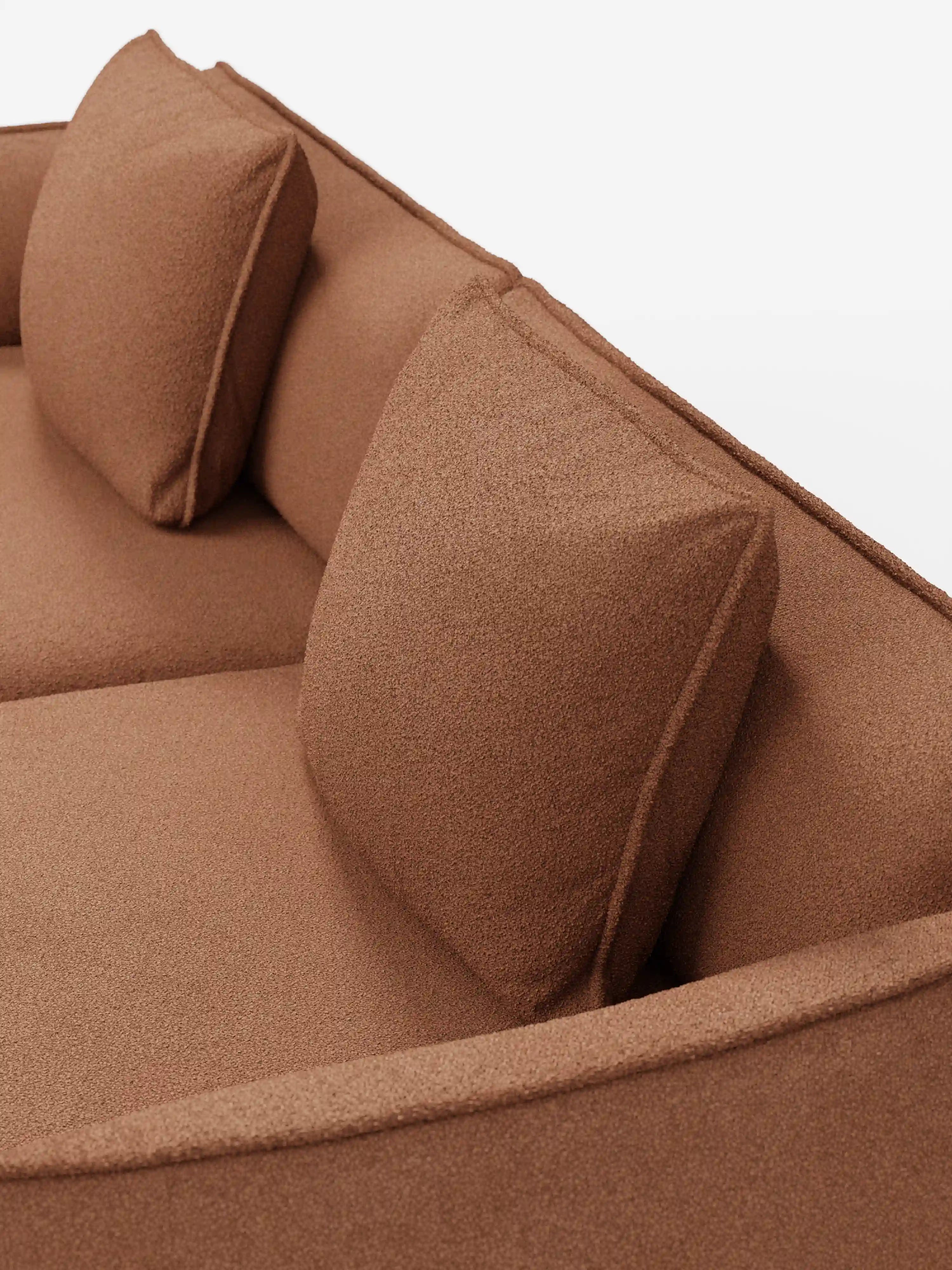 Un primo piano del divano modulare e componibile a 3 posti Nimbus di Divani.Store, presentato in una moderna finitura marrone sfoderabile, in tessuto smacchiabile effetto cotone T33. Il divano presenta due cuscini dello schienale quadrati e ampi braccioli, ripresi dall’alto su uno sfondo bianco a tinta unita. Il tessuto testurizzato e i cuscini disposti con cura accentuano lo stile contemporaneo del divano.