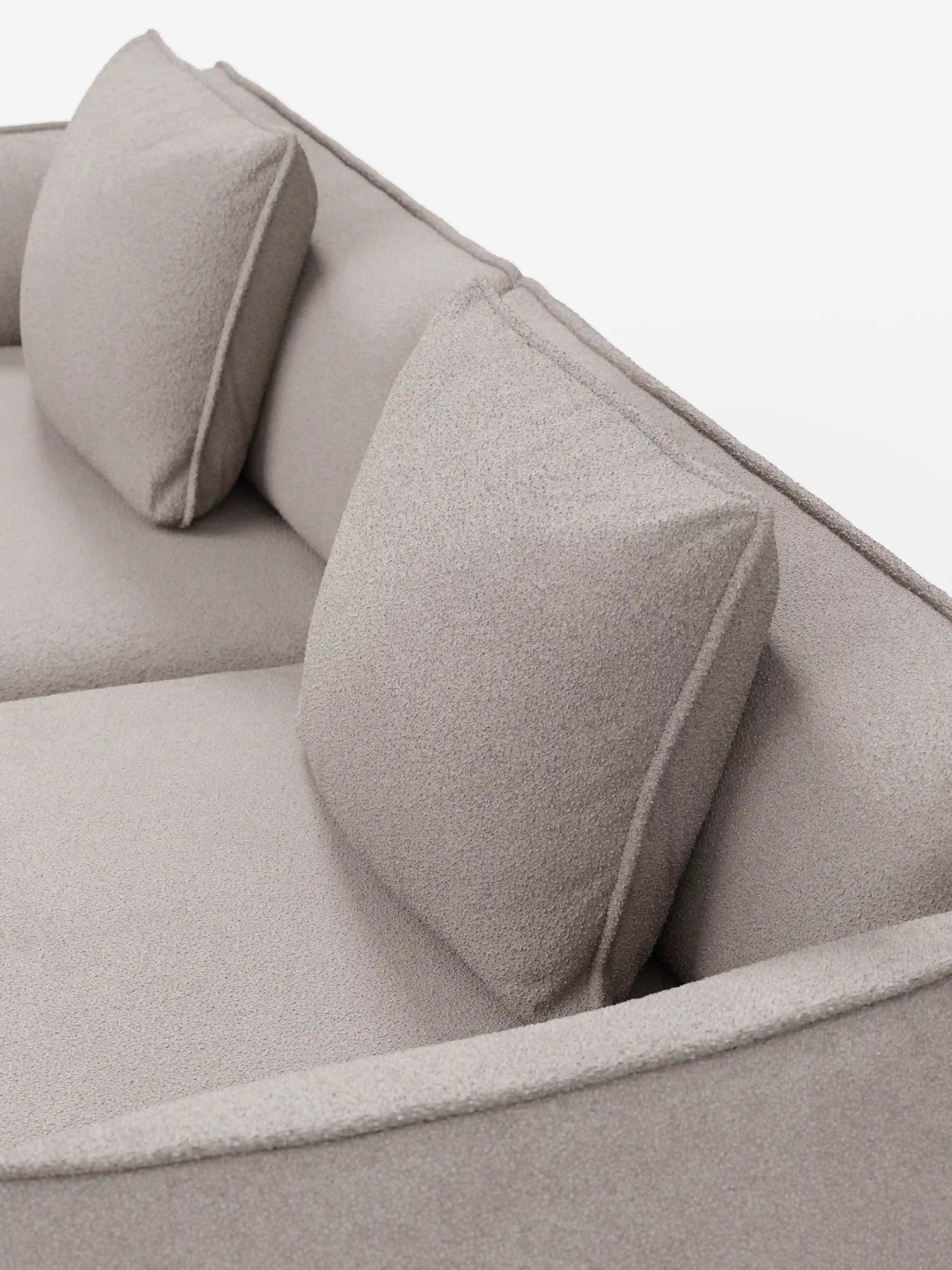 Primo piano del divano modulare e componibile Nimbus a 3 posti di Divani.Store, qui presentato in un moderno tessuto t33 beige effetto cotone, resistente alle macchie. Caratterizzato da due cuscini schienali quadrati, questo divano da 250 cm si distingue per il rivestimento testurizzato, le linee pulite e il design minimalista su uno sfondo bianco a tinta unita.