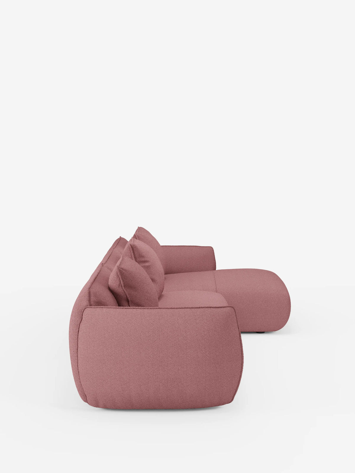 Vista laterale del divano angolare con penisola componibile Nimbus di Divani.Store, rivestito in morbido tessuto T33 effetto cotone, resistente alle macchie. Il divano presenta una silhouette moderna con bordi arrotondati, una seduta profonda e due cuscini coordinati. Su uno sfondo bianco a tinta unita, l’immagine mette in risalto la texture morbida e il design minimalista di questo divano contemporaneo. Nella scena non sono visibili altri oggetti.