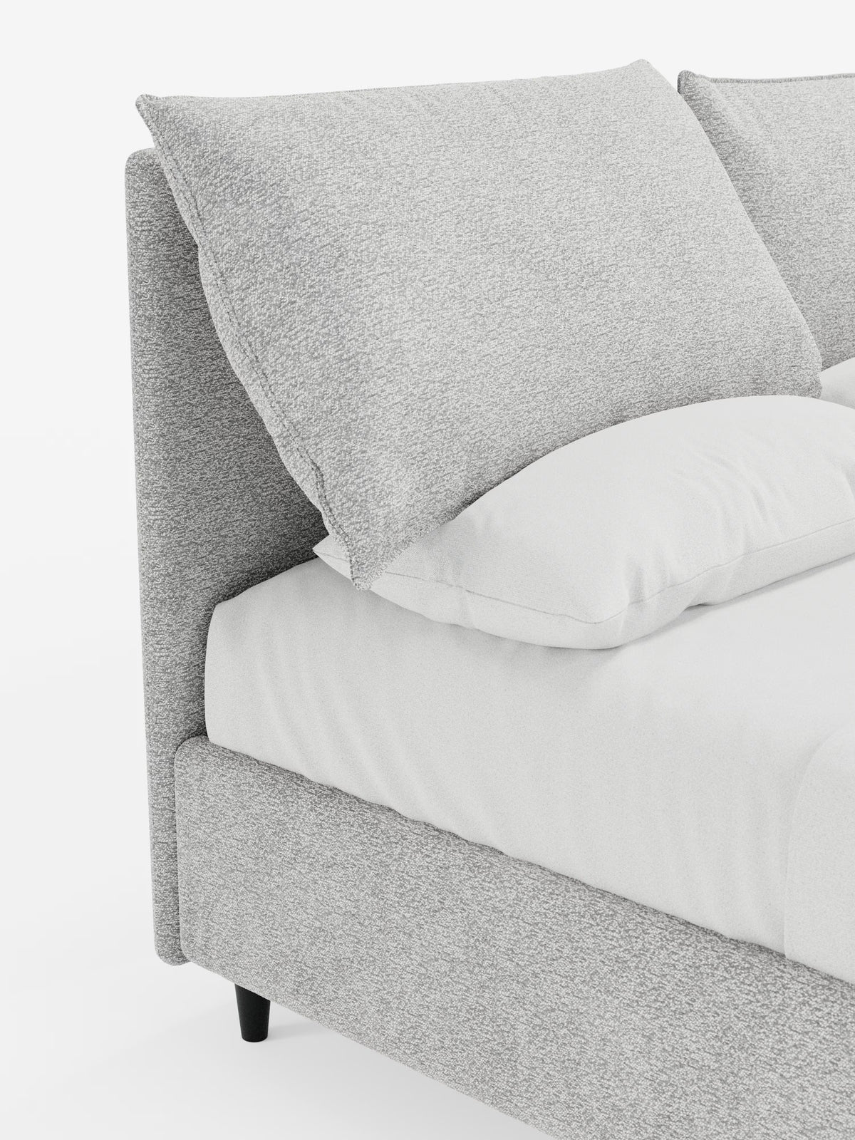 Primo piano del letto imbottito ZAYRON con contenitore e morbidi cuscini regolabili di Letti.store, caratterizzato da un design moderno con testiera e struttura imbottite in grigio chiaro, certificate Oeko-Tex®. Il letto è abbellito da un grande cuscino grigio angolare, un cuscino bianco e biancheria da letto candida. Poggia su brevi gambe nere su uno sfondo bianco a tinta unita, che ne esalta le texture morbide e le linee pulite.