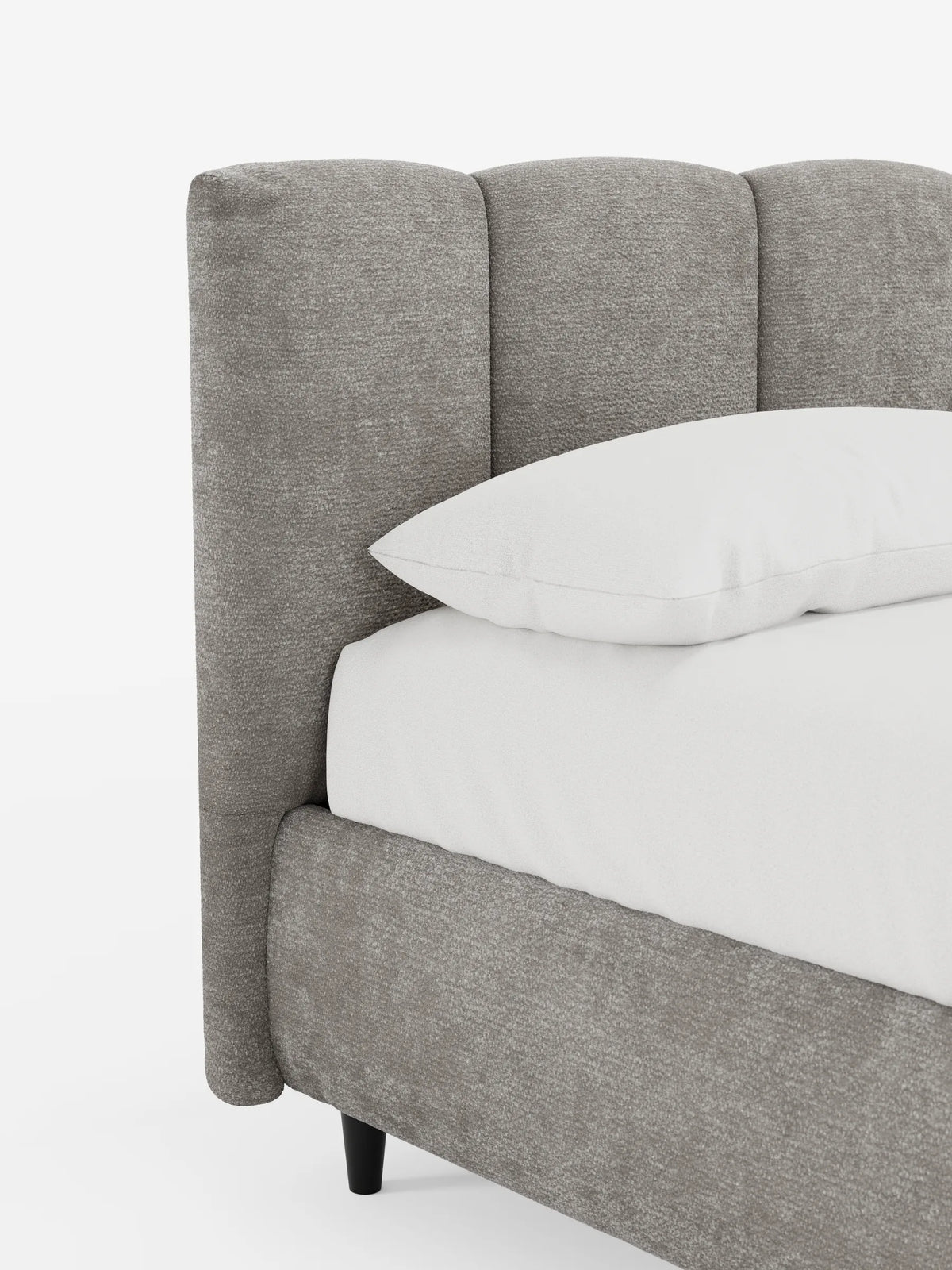 Un letto ARKAM imbottito di colore grigio, dotato di vano contenitore e testiera a pannelli verticali, presenta una testiera a pannelli verticali con finitura in tessuto testurizzato, un cuscino bianco e biancheria da letto di un bianco brillante su uno sfondo chiaro.