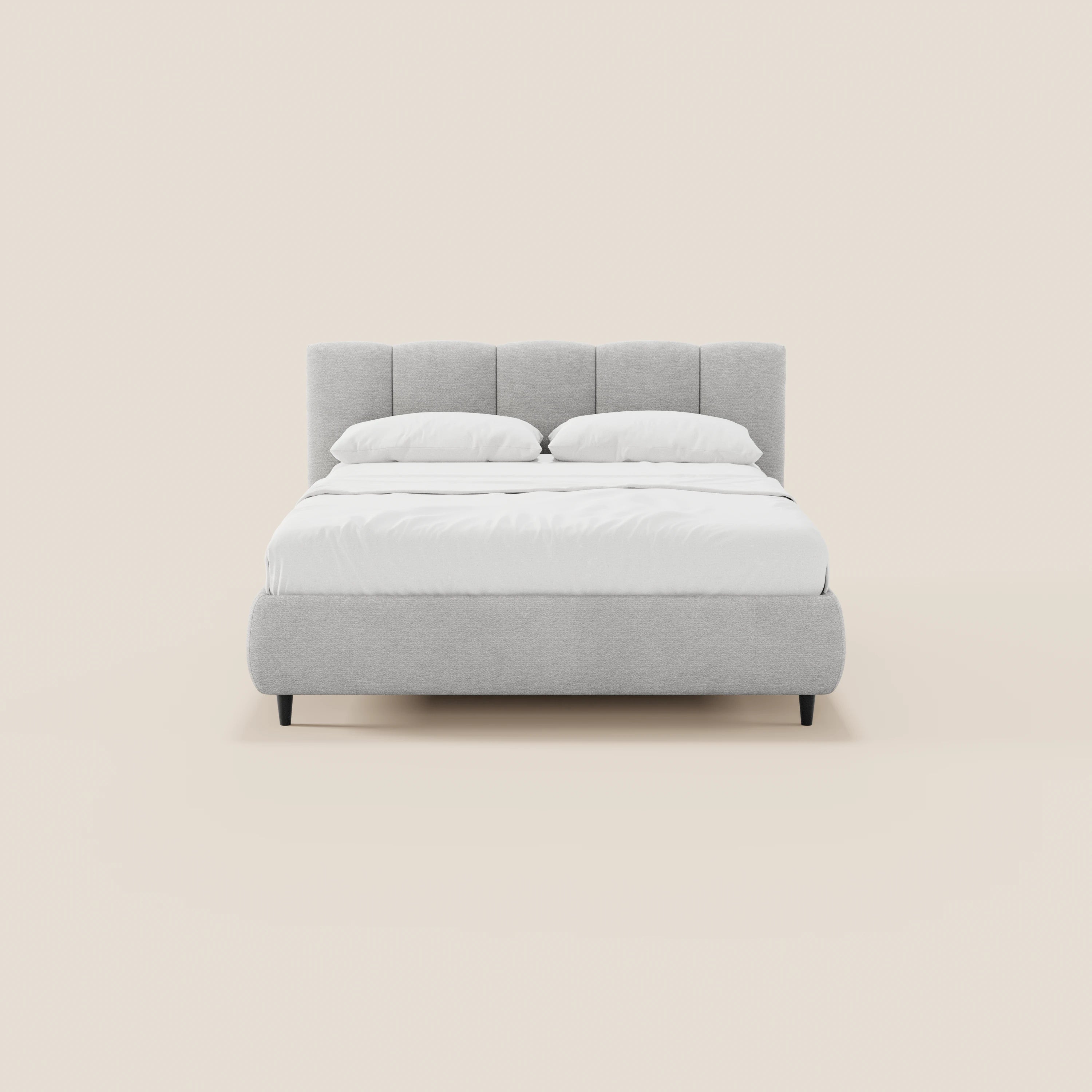 Il letto imbottito ARKAM di Letti.store presenta un design shabby chic in tessuto Oeko-Tex®, con una testiera alta a cuciture verticali, una base contenitiva, un rivestimento grigio chiaro e gambe corte nere. Abbinato a biancheria da letto bianca e due cuscini su uno sfondo beige.