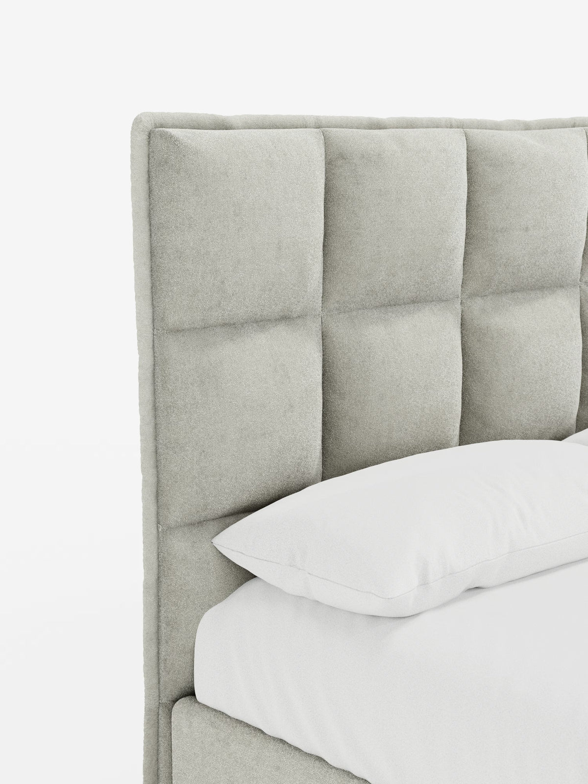 Primo piano del letto AURO di Letti.store, caratterizzato da una testiera alta imbottita di colore grigio chiaro con trapuntatura a quadrati in ciniglia Oeko-Tex®, che richiama il classico effetto capitonné. Un cuscino bianco e una parte del materasso bianco mettono in risalto la morbida trama e il design contemporaneo e minimalista. Lo sfondo è bianco a tinta unita.