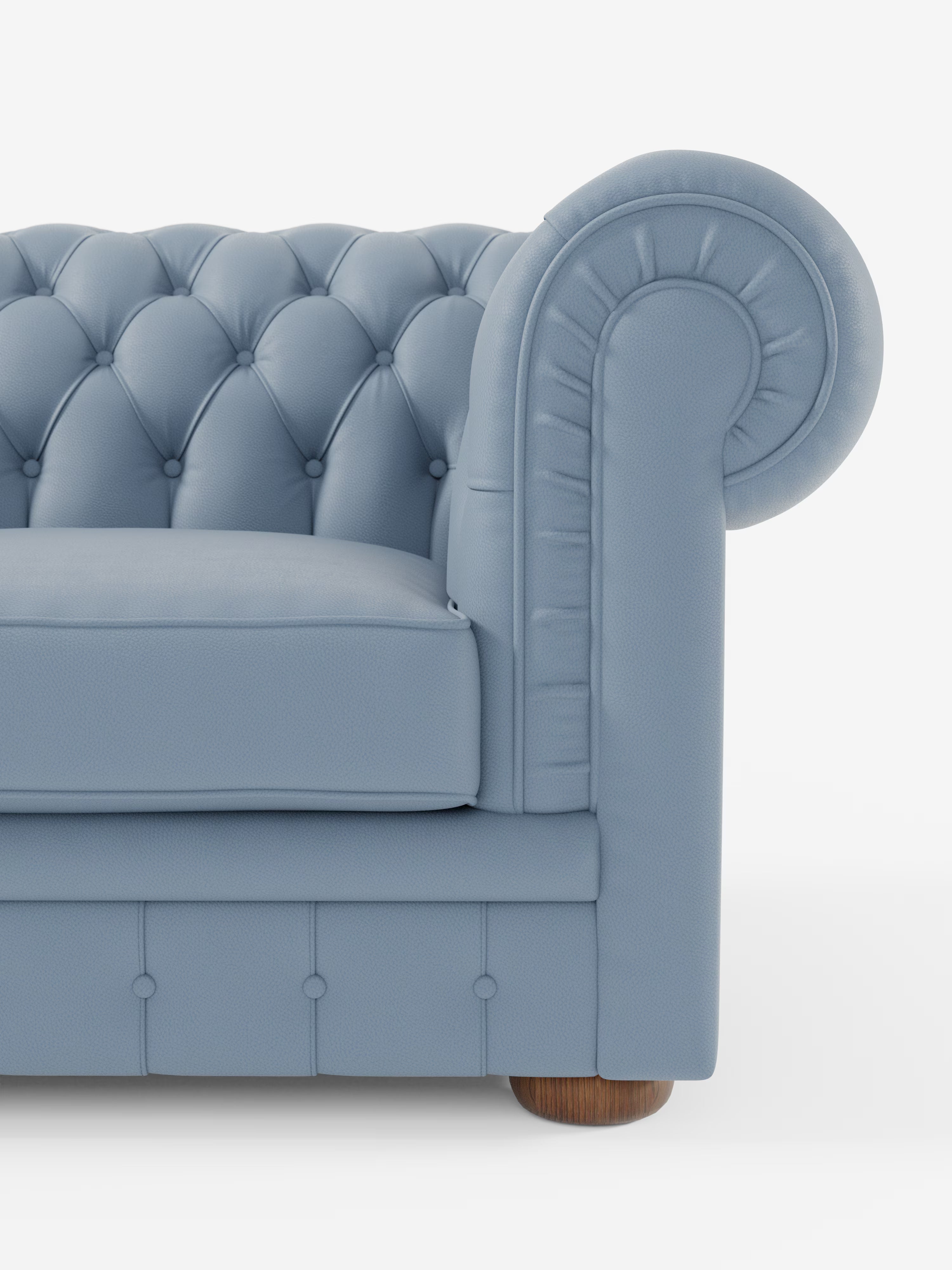 Primo piano di un Chesterfield azzurro – Divano Chesterfield in vera pelle spessorata a 2 e 3 posti di Divani.Store, che mette in risalto lo schienale capitonné, i braccioli arrotondati con dettagli plissettati, il cuscino di seduta rigido, i bottoni decorativi e le gambe corte in legno su uno sfondo bianco a tinta unita. È visibile solo il lato sinistro di questo divano artigianale Made in Italy.