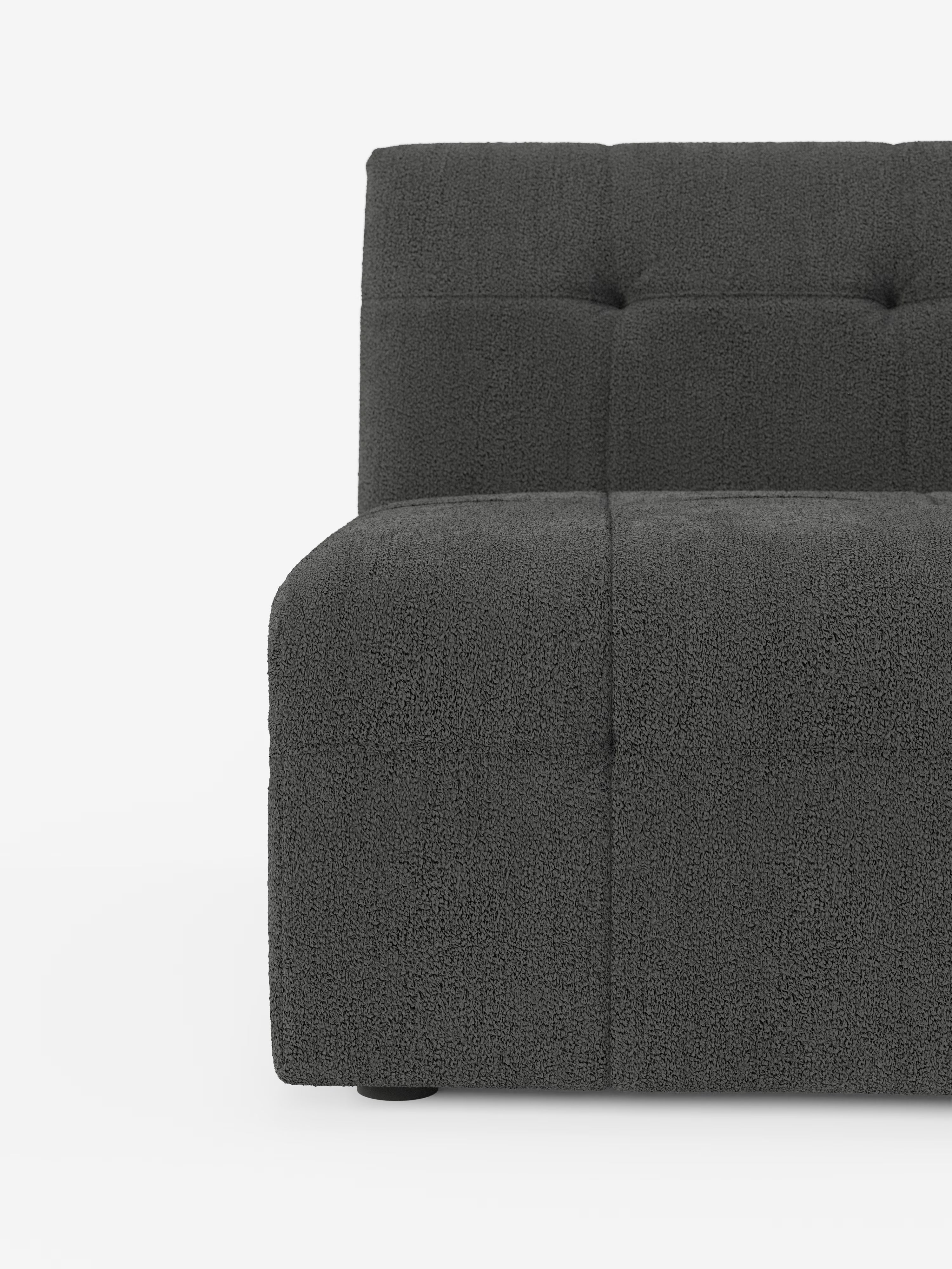 Un primo piano del lato sinistro della poltrona Mosaic modulo da 77 cm in bouclé di Divani.Store ne mette in risalto il design moderno, realizzato in tessuto T21 grigio scuro smacchiabile, con un rivestimento morbido e testurizzato che ricorda il bouclé e un’elegante trapuntatura quadrata capitonné. Su uno sfondo bianco a tinta unita sono visibili solo una parte della seduta, dello schienale e del bracciolo.