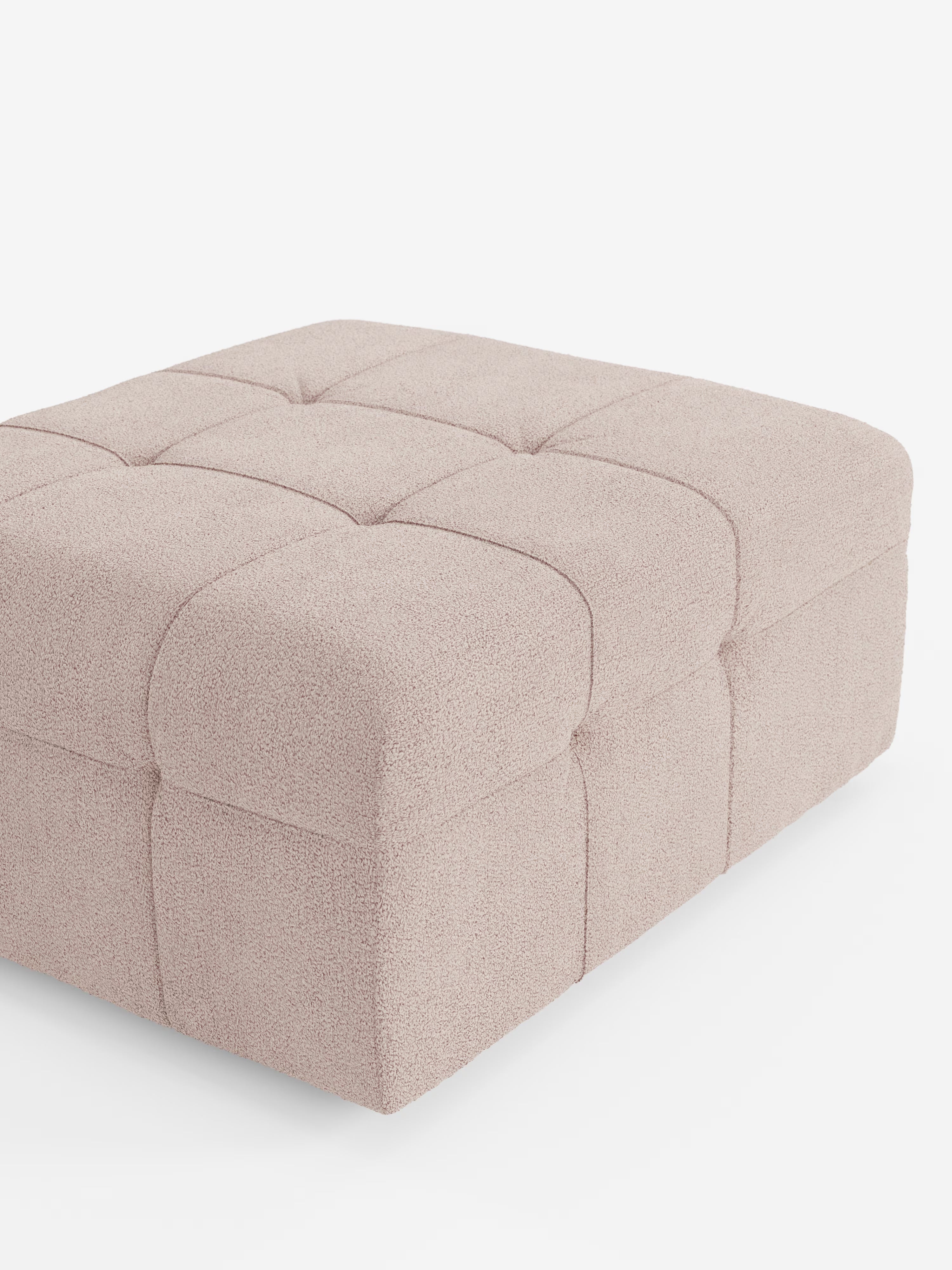 Un grande pouf quadrato “Mosaic” di Divani.Store, dalle dimensioni di 96x77 cm e rivestito in tessuto bouclé T21 beige chiaro, resistente alle macchie, con lavorazione capitonné su superficie e fianchi, spicca su uno sfondo bianco a tinta unita. È visibile solo una parte di questo lussuoso e moderno complemento d’arredo di produzione italiana, a sottolineare la sua raffinata lavorazione artigianale.