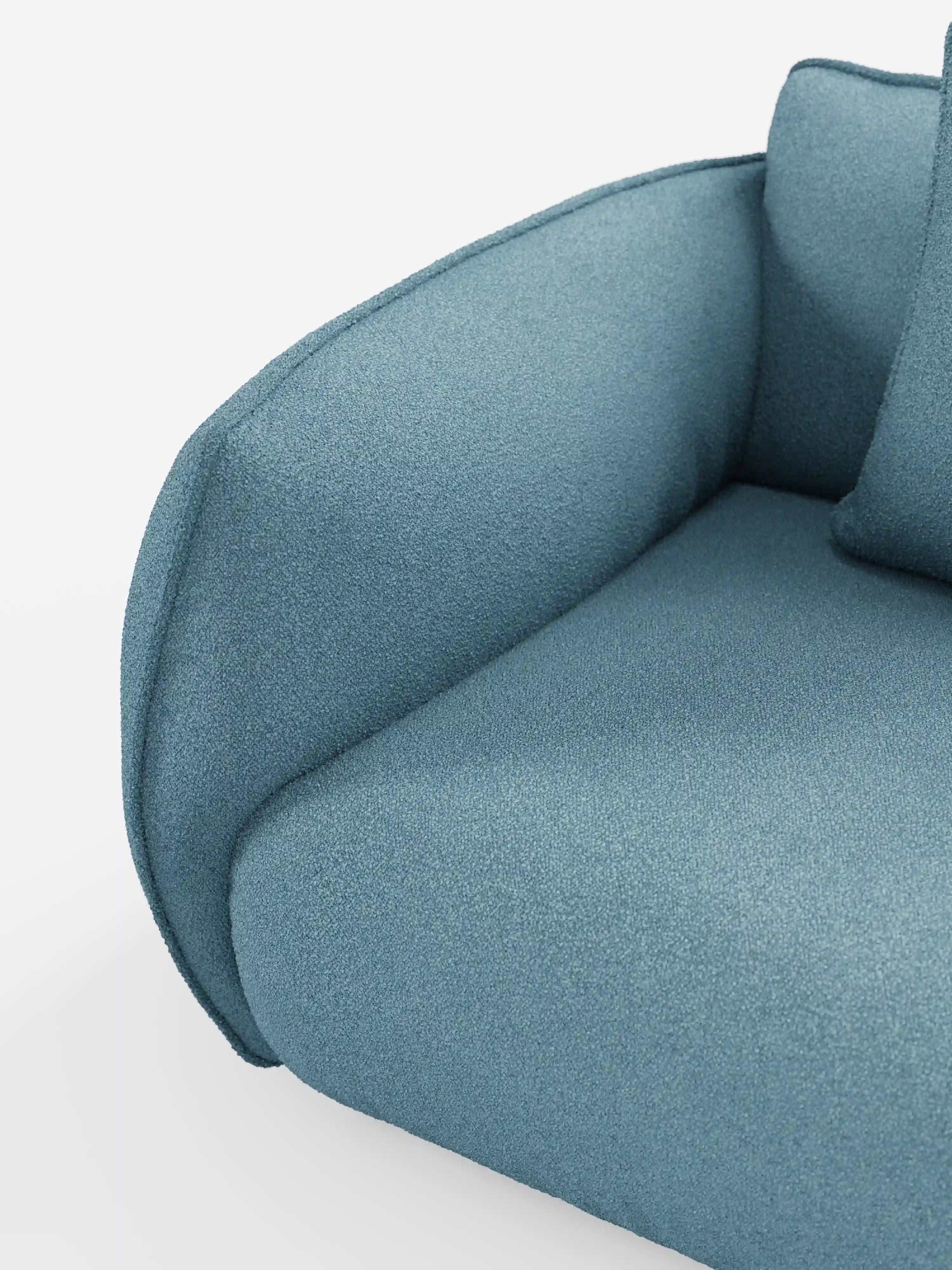 Primo piano del divano modulare e componibile Nimbus a 3 posti di Divani.Store, lungo 250 cm e rivestito in tessuto sfoderabile e antimacchia effetto cotone t33 di colore blu. Il divano presenta un bracciolo arrotondato e un cuscino coordinato, con un rivestimento testurizzato che ne esalta le linee morbide e sinuose e l’imbottitura soffice. In primo piano su uno sfondo bianco a tinta unita.