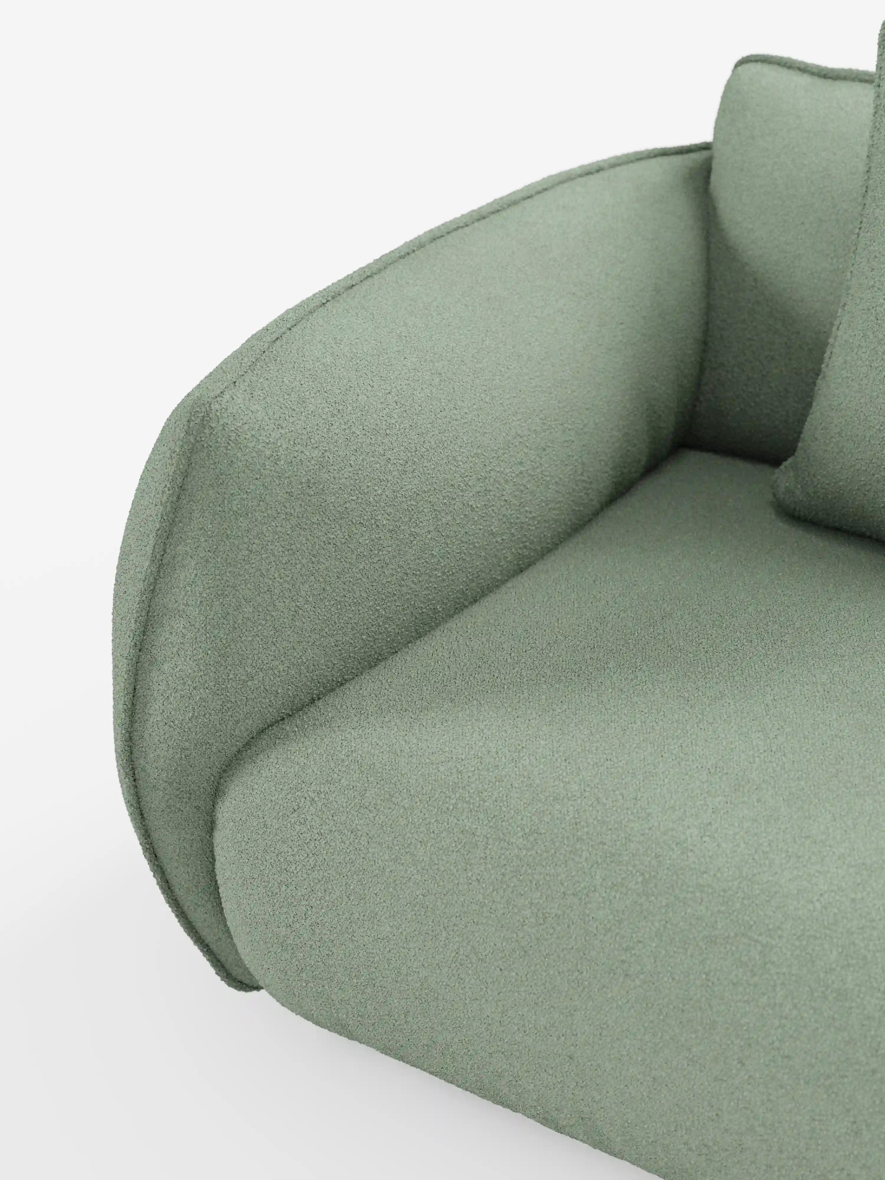 Primo piano del divano Nimbus a 3 posti, modulare e componibile, di Divani.Store, in un moderno verde salvia, rivestito in morbido tessuto effetto cotone antimacchia (tessuto smacchiabile effetto cotone t33). L'immagine mette in risalto il bracciolo ricurvo, il cuscino di seduta e parte di un cuscino su uno sfondo bianco, esaltandone il design lussuoso ma minimalista.
