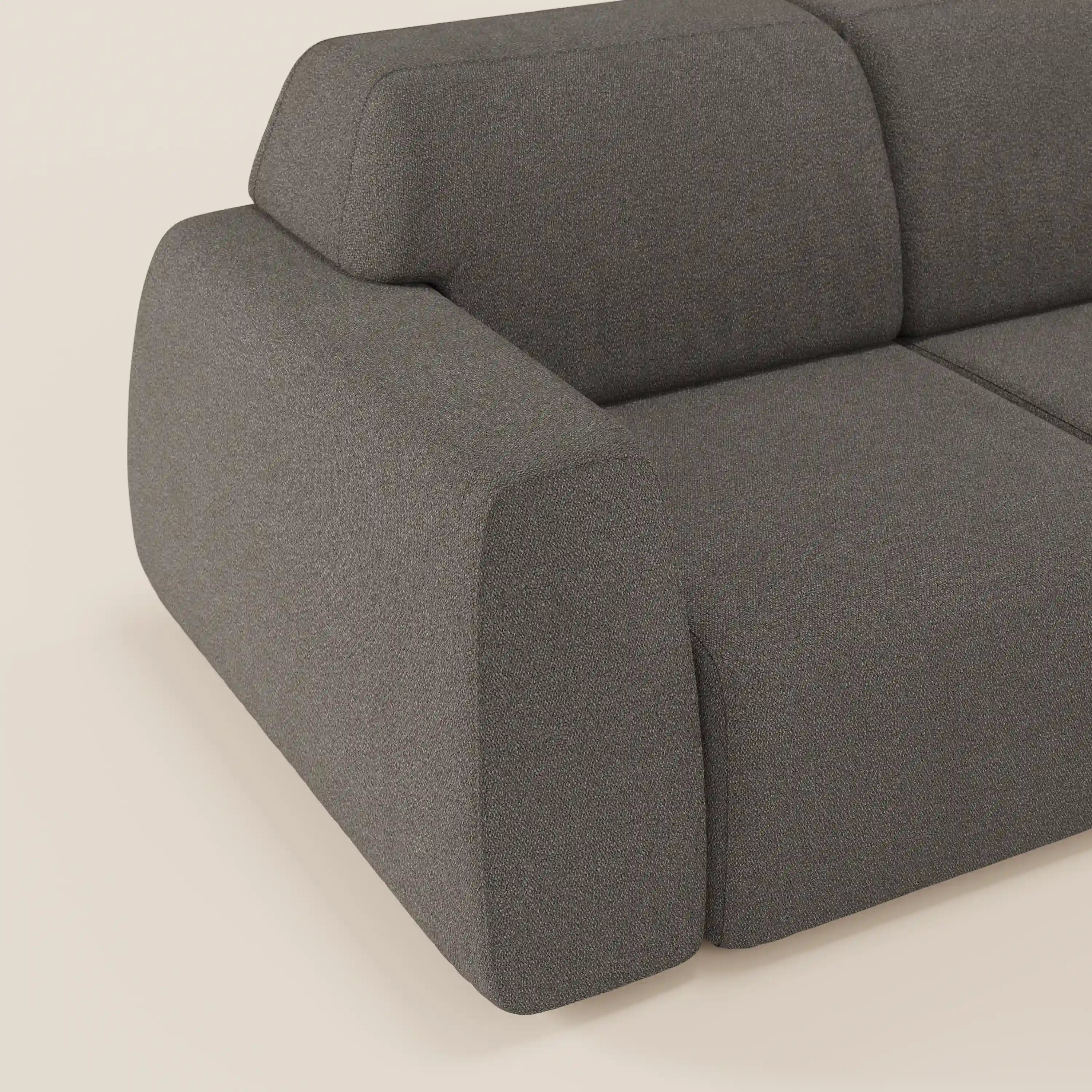 Un primo piano di Orbit Divano angolare con penisola reversibile di Divani.Store mostra il suo design liscio e arrotondato, il tessuto grigio scuro smacchiabile effetto cotone T33 e le sedute regolabili su un pavimento e una parete chiari.