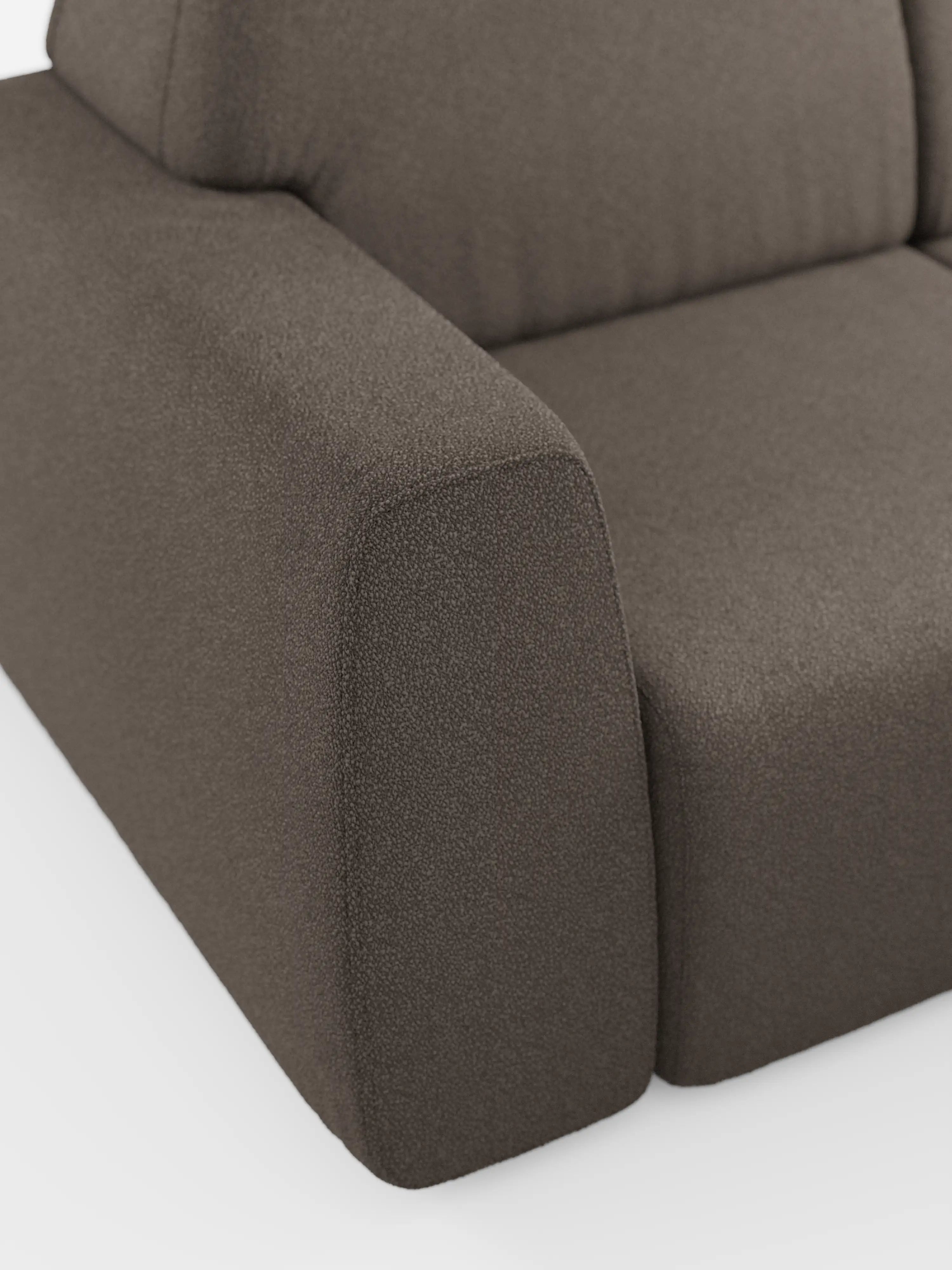 Primo piano del divano angolare Orbit con penisola reversibile e tutte le sedute allungabili in tessuto smacchiabile effetto cotone T33 di Divani.Store, che mette in risalto l'angolo imbottito marrone con bracciolo a vista, cuscino di seduta e parte dello schienale. Il tessuto antimacchia effetto cotone presenta un aspetto raffinato e strutturato su uno sfondo bianco. Questo divano modulare vanta un design moderno dalle linee pulite e spigolose che esaltano la maestria artigianale e lo stile di alta gamma.