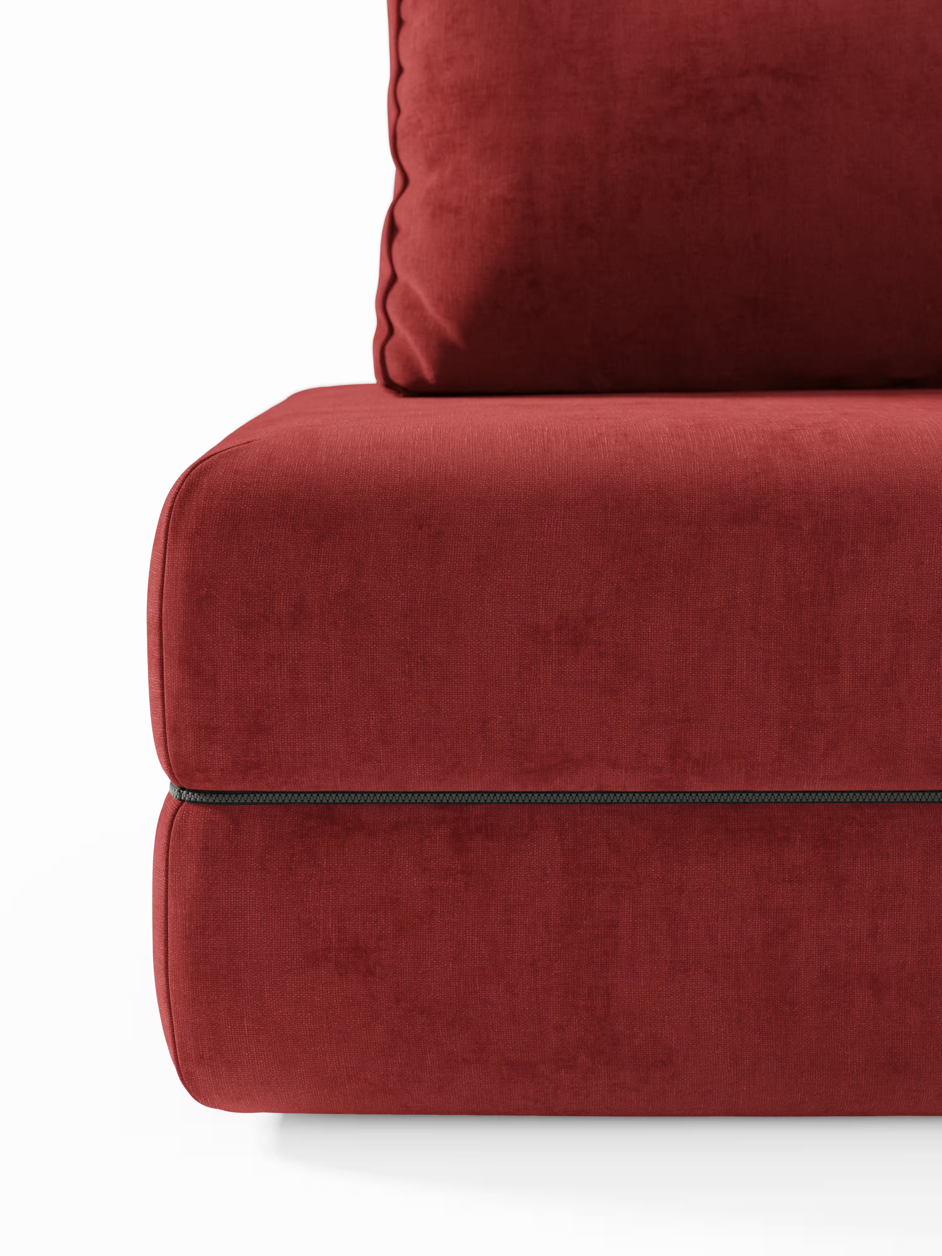 Primo piano di un cuscino in velluto rosso della linea Rift, divano letto matrimoniale a 2 e 3 posti con schienali mobili di Divani.Store, caratterizzato da una cucitura in evidenza e da un bordino lungo il perimetro. Il cuscino, morbido e spesso, realizzato in tessuto soffice, è completato da un grande cuscino coordinato appoggiato allo schienale. Fa parte di un elegante divano letto dotato di un materasso in memory foam alto 22 cm nella versione T31. Lo sfondo è bianco e essenziale.