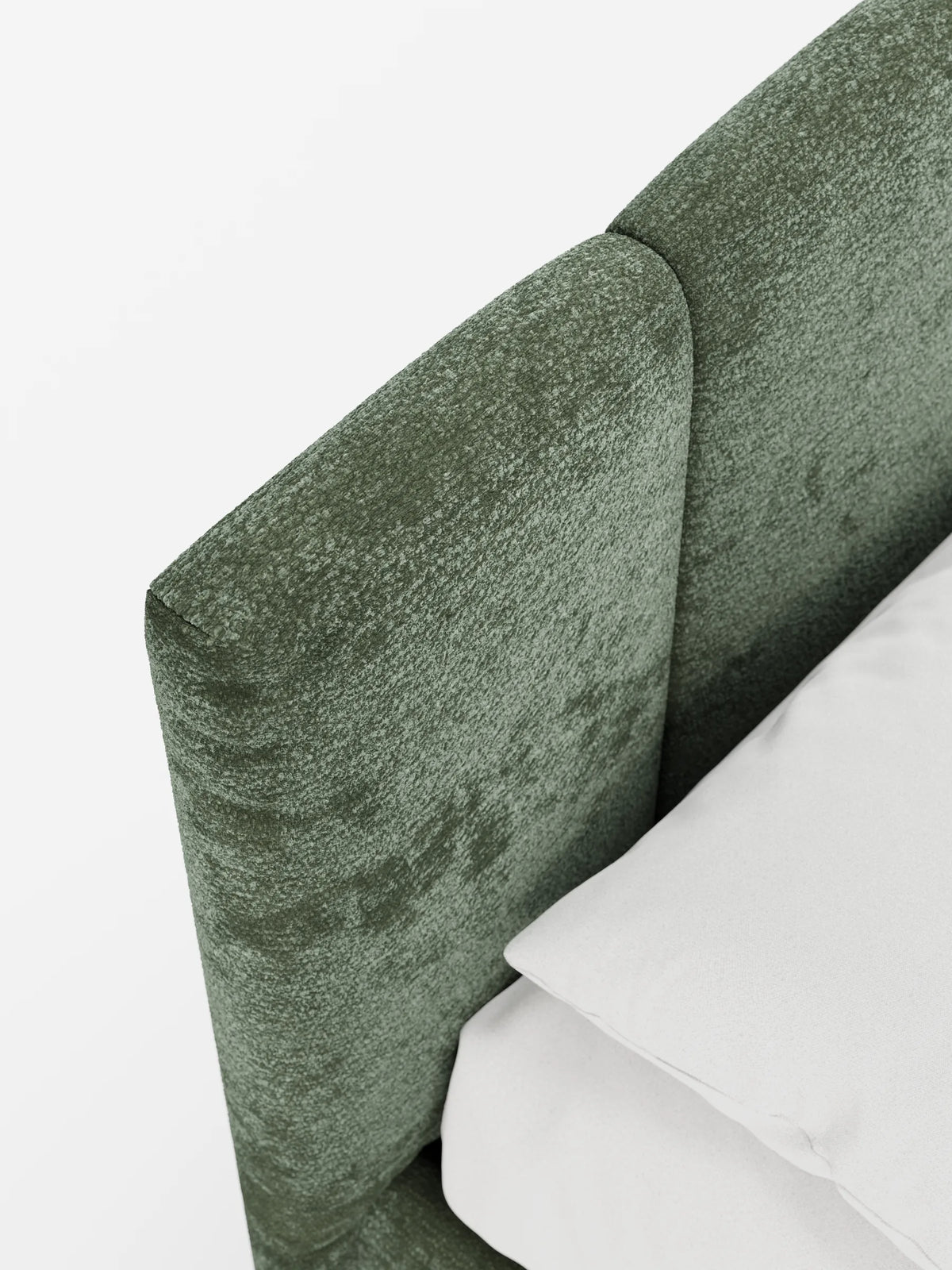Primo piano del letto imbottito ARKAM con contenitore e testiera a lavorazione verticale in tessuto testurizzato color verde salvia, con un angolo di un cuscino bianco appoggiato sulla sua superficie morbida e opaca.