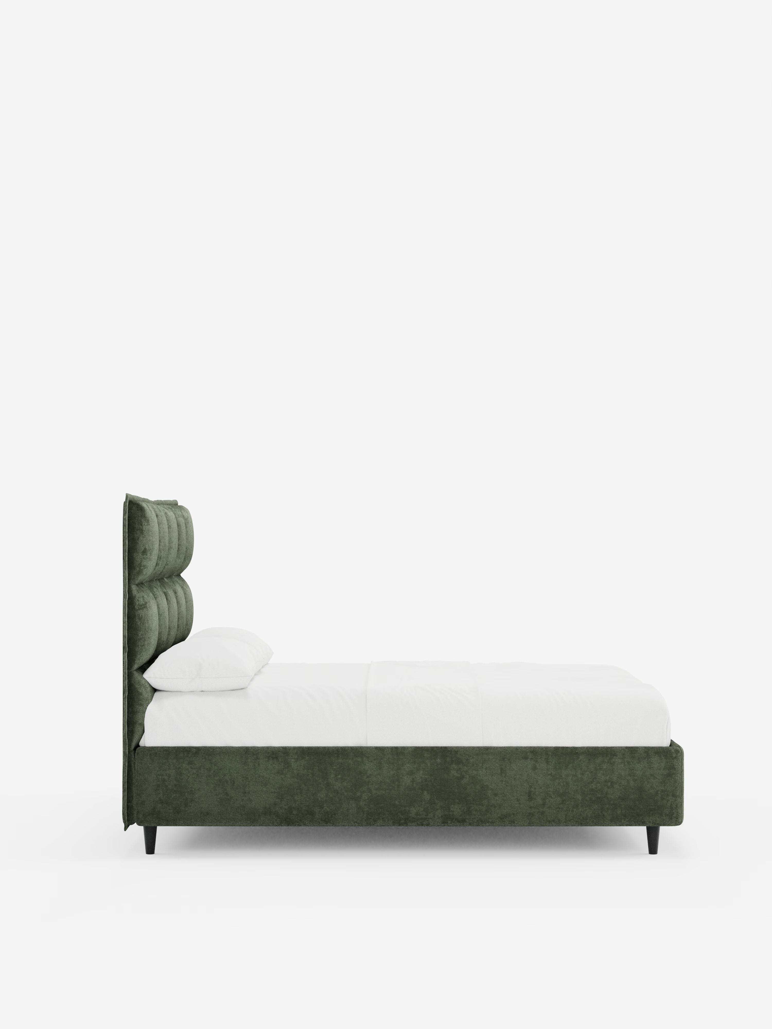 Vista laterale del letto imbottito AURO con contenitore e testiera capitonné alta in ciniglia Oeko-Tex® di Letti.store, caratterizzato da una moderna struttura imbottita verde scuro e da un’alta testiera capitonné in stile classico. Il letto è rivestito con biancheria da letto bianca e due cuscini e poggia su corte gambe nere. Sullo sfondo di un semplice muro bianco, questo elegante letto imbottito con contenitore diventa il punto focale della stanza.
