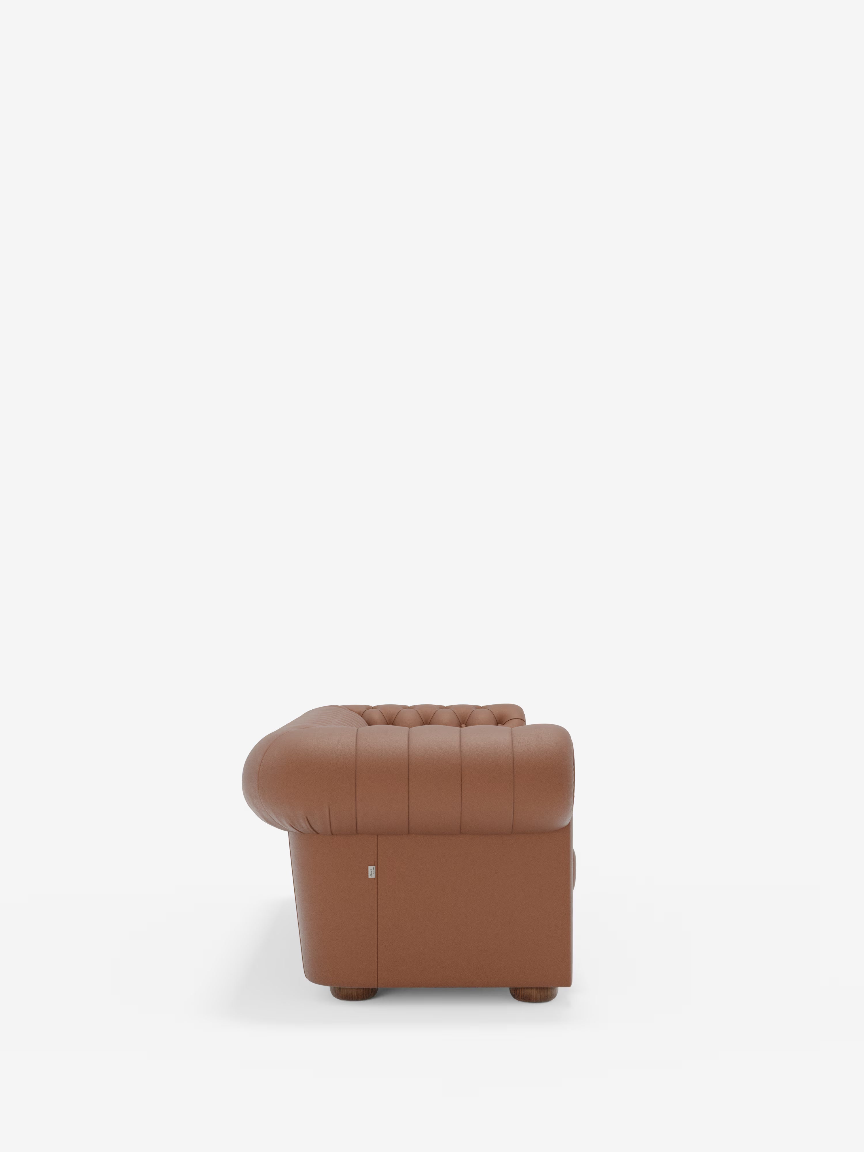 Vista laterale di una poltrona in pelle marrone capitonné della linea Chester – Divano Chesterfield in vera pelle spessorata a 2 e 3 posti di Divani.Store, caratterizzata da schienale e braccioli arrotondati e raffigurata su uno sfondo bianco. Sono visibili solo un bracciolo e parte del cuscino di seduta, mentre le gambe non sono visibili. Richiamando l’eleganza classica dei divani artigianali Made in Italy, questo modello emana il fascino intramontabile caratteristico dell’autentico design Chesterfield.