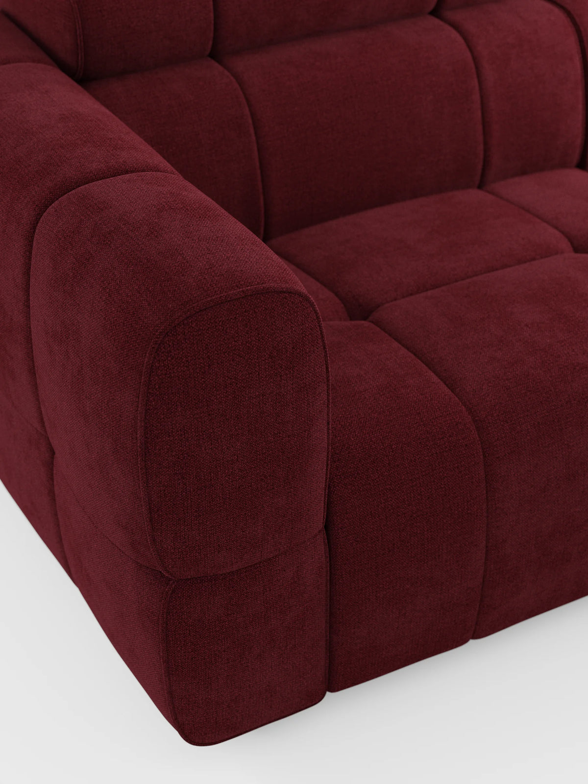 Un divano modulare Giotto a 4 posti con poggiatesta reclinabili e funzione relax elettrica opzionale, rivestito in tessuto smacchiabile T23 color bordeaux intenso con motivo a quadretti trapuntati, braccioli arrotondati e cuscini spessi su uno sfondo chiaro.