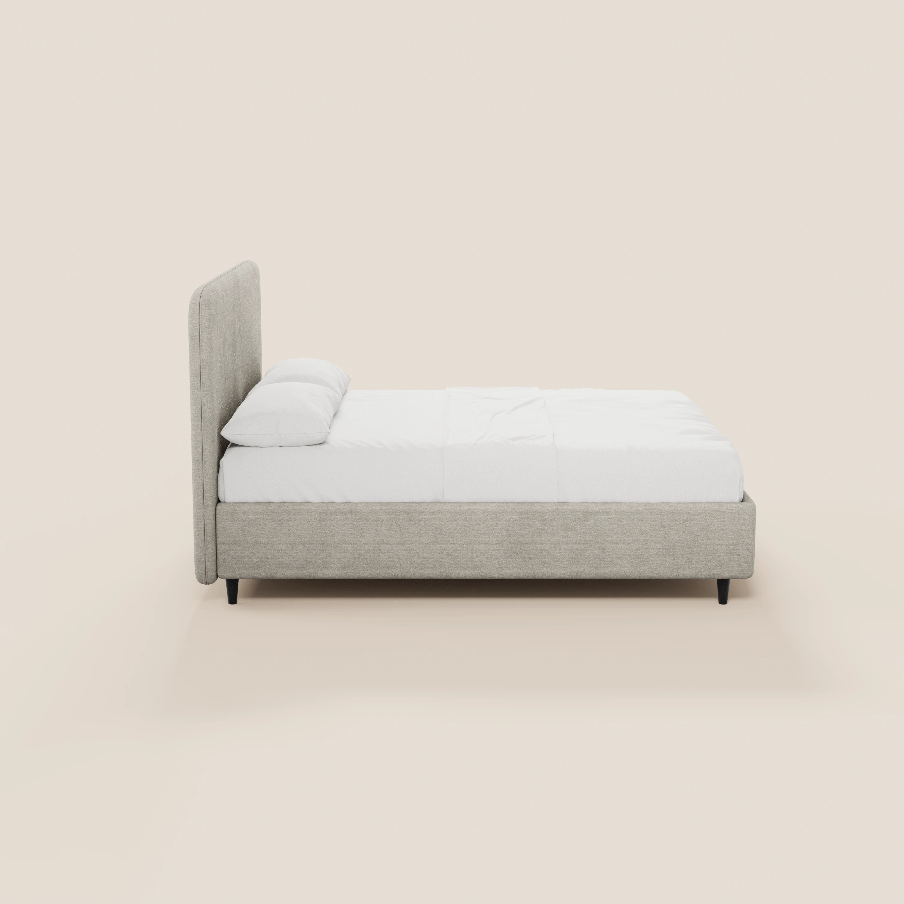 Vista laterale del letto KAELOS minimal imbottito di Letti.store, caratterizzato da una testiera alta e arrotondata in ciniglia, biancheria da letto bianca con due cuscini, gambe alte nere e vano contenitore; il tutto su uno sfondo beige chiaro.