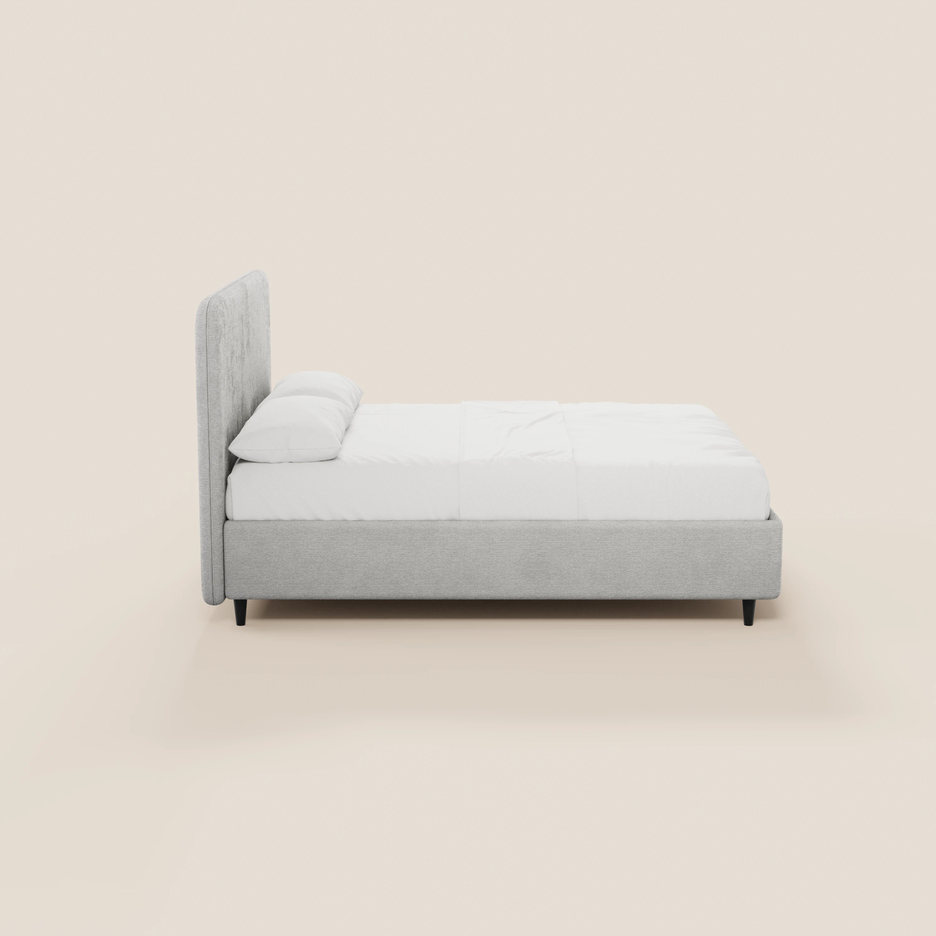 Il letto imbottito KAELOS minimal di Letti.store è presentato in ciniglia grigio chiaro con testiera arcuata, biancheria da letto e cuscini bianchi, gambe alte nere e un vano contenitore, il tutto su uno sfondo beige chiaro a tinta unita.