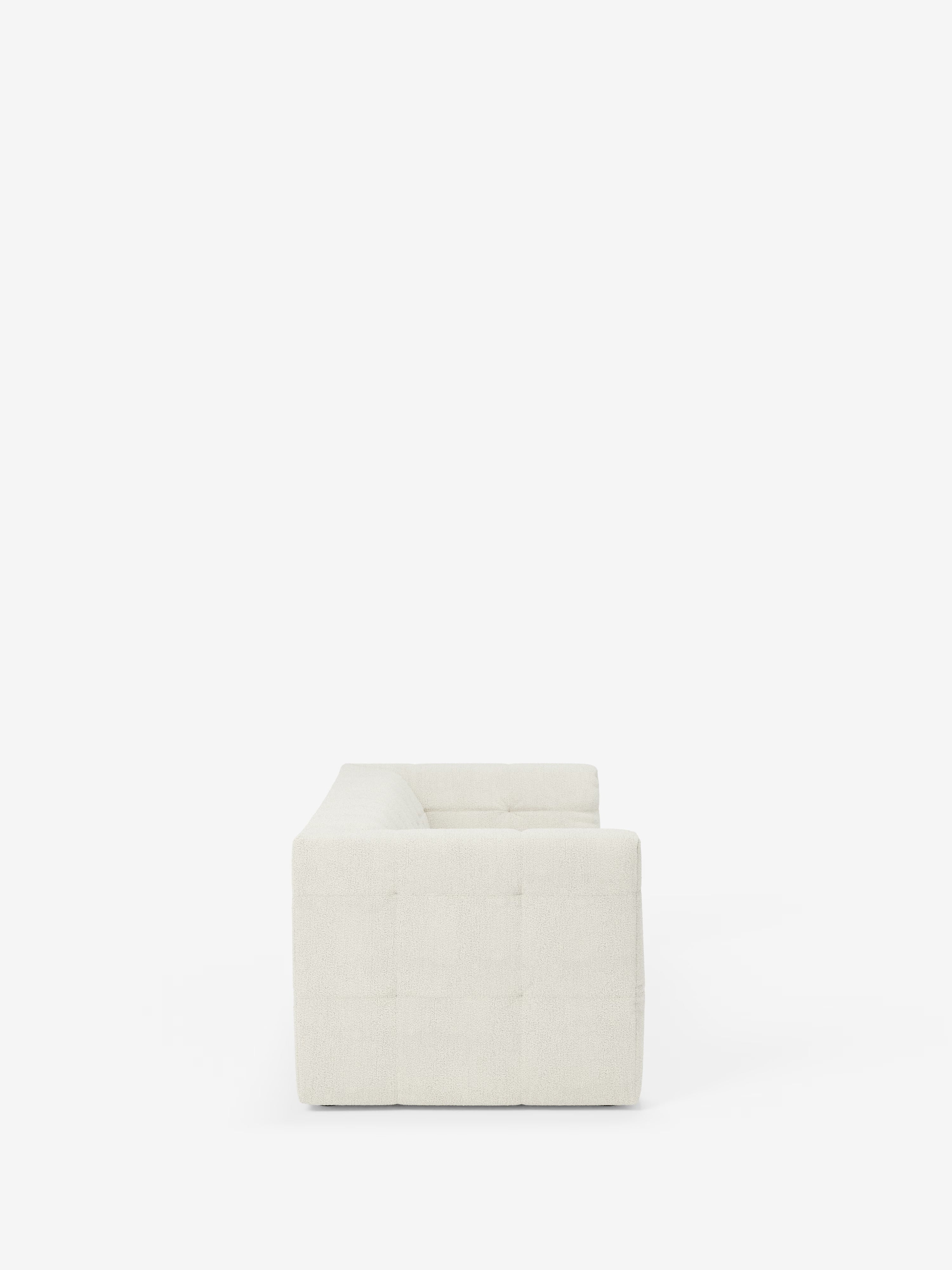 Vista laterale del divano modulare Mosaic a 3 e 4 posti in bouclé di Divani.Store, caratterizzato da una silhouette moderna e minimalista con una forma squadrata e cuciture capitonné a griglia. Il tessuto T21 bianco sporco e resistente alle macchie ne esalta le linee pulite e la consistenza morbida, con il design modulare che spicca su uno sfondo bianco.