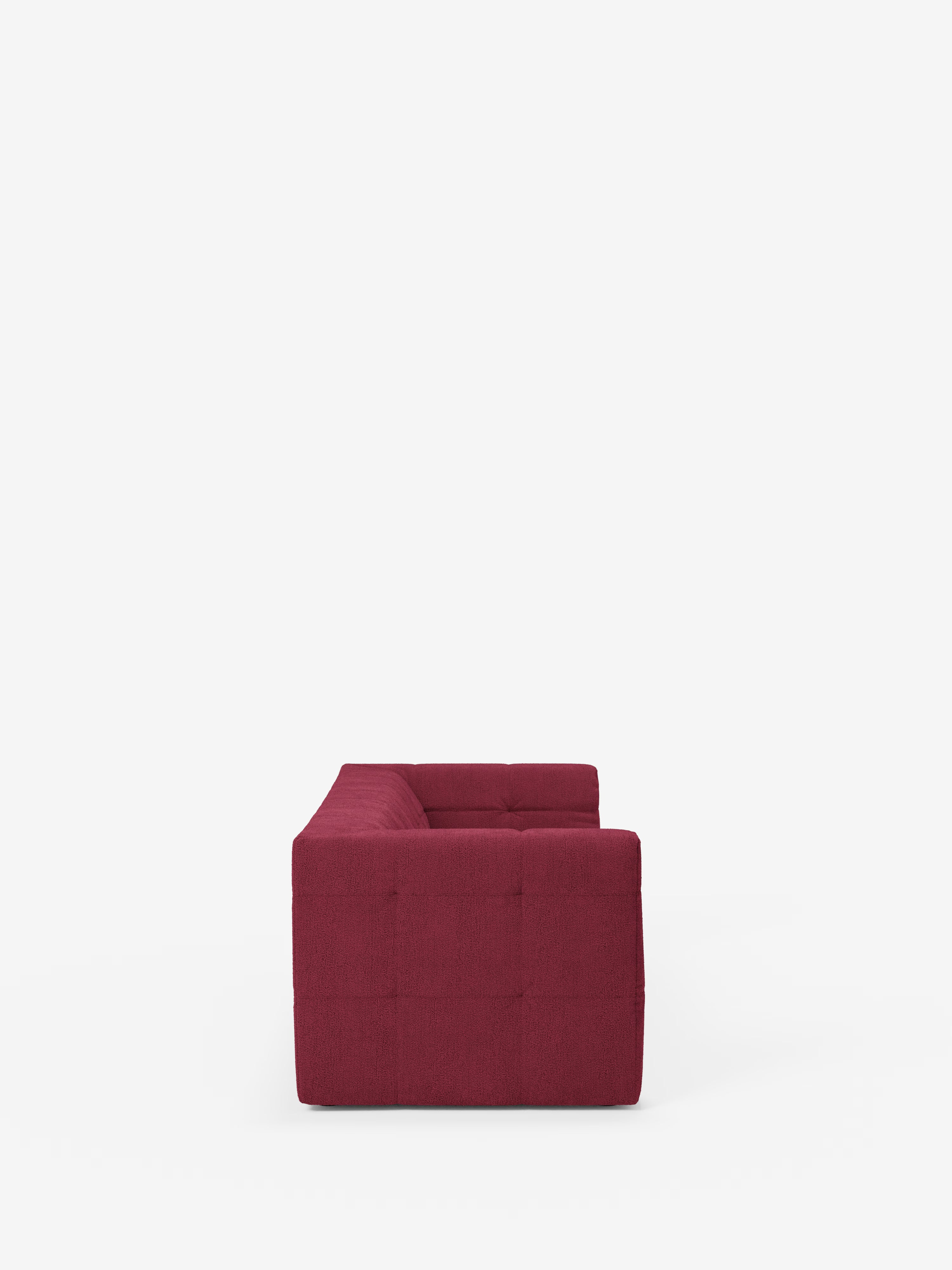 Vista laterale del divano modulare Mosaic a 3 e 4 posti in bouclé di Divani.Store, caratterizzato da una silhouette squadrata di colore rosso intenso, dal design minimalista e da un motivo capitonné a griglia su tessuto T21 antimacchia, che risalta su uno sfondo bianco a tinta unita.