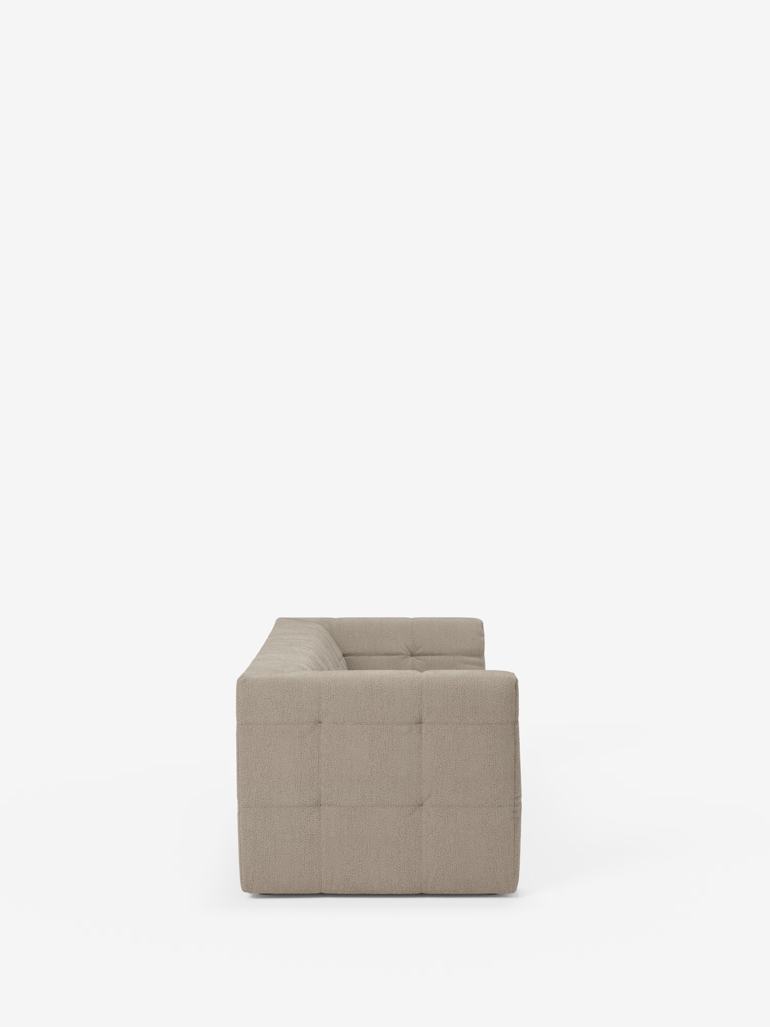 Il divano modulare Mosaic Divano a 3 e 4 posti in bouclé, di colore beige e dal design moderno, realizzato da Divani.Store, è raffigurato di profilo su uno sfondo bianco a tinta unita. Questo divano contemporaneo presenta una silhouette squadrata con una caratteristica cucitura capitonné sui pannelli laterali, che crea un effetto trapuntato. I braccioli e lo schienale sono posizionati alla stessa altezza, sottolineando le sue linee pulite e il design moderno, realizzato in tessuto T21 facile da pulire.