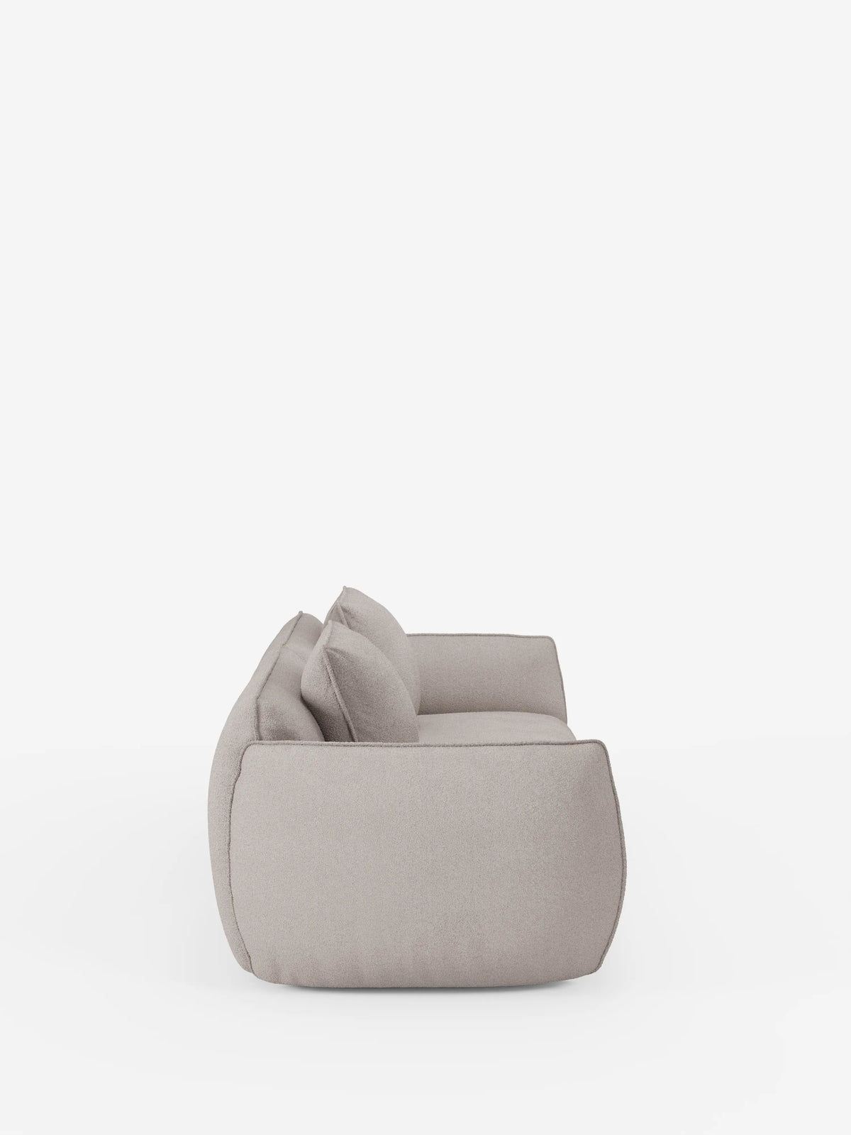 Vista laterale del divano Nimbus a 3 posti, modulare e componibile da 250 cm di Divani.Store, qui raffigurato in un tessuto moderno color beige chiaro con cuscini morbidi e bordi arrotondati. Il divano, rivestito in tessuto t33 effetto cotone, sfoderabile e resistente alle macchie, ha un'altezza ridotta da terra e un aspetto morbido e accogliente. È ripreso su uno sfondo bianco a tinta unita, senza altri oggetti visibili.