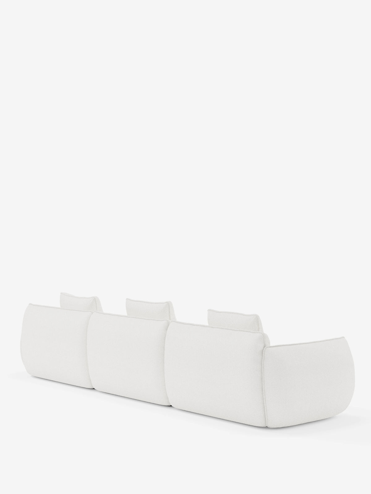 Un divano bianco contemporaneo e minimalista — il divano angolare con penisola componibile Nimbus in morbido tessuto effetto cotone smacchiabile T33 di Divani.Store — è ripreso di spalle su uno sfondo bianco a tinta unita. Caratterizzato da tre schienali separati e braccioli bassi e ampi, questo elegante modello unisce comfort pratico e lusso discreto, rendendolo perfetto per qualsiasi ambiente moderno.