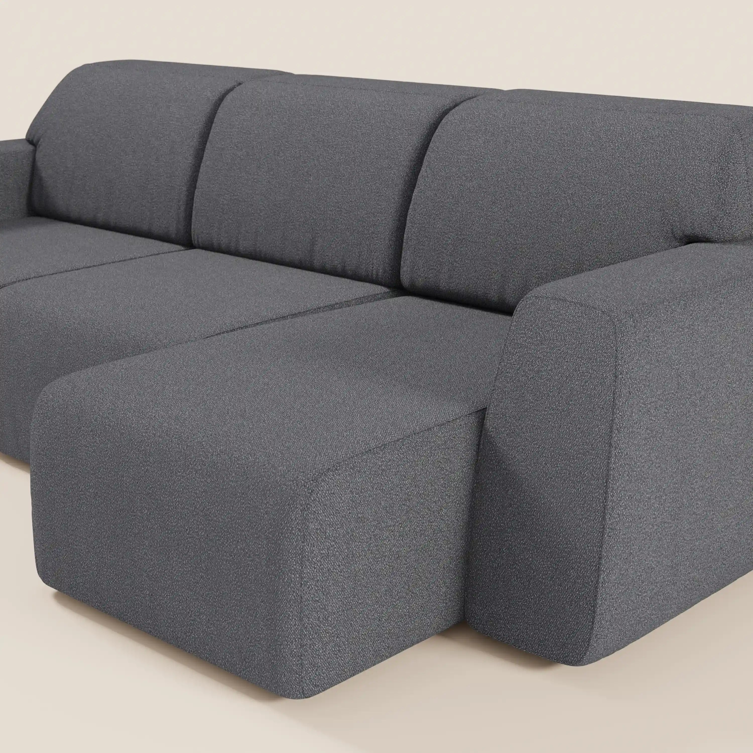 Il divano Orbit di Divani.Store è caratterizzato da 3 sedute allungabili indipendentemente in tessuto T33 antimacchia effetto cotone. Le sue ampie e morbide sedute e il suo design minimalista offrono un ampio comfort, qui rappresentato in grigio scuro su uno sfondo beige chiaro.
