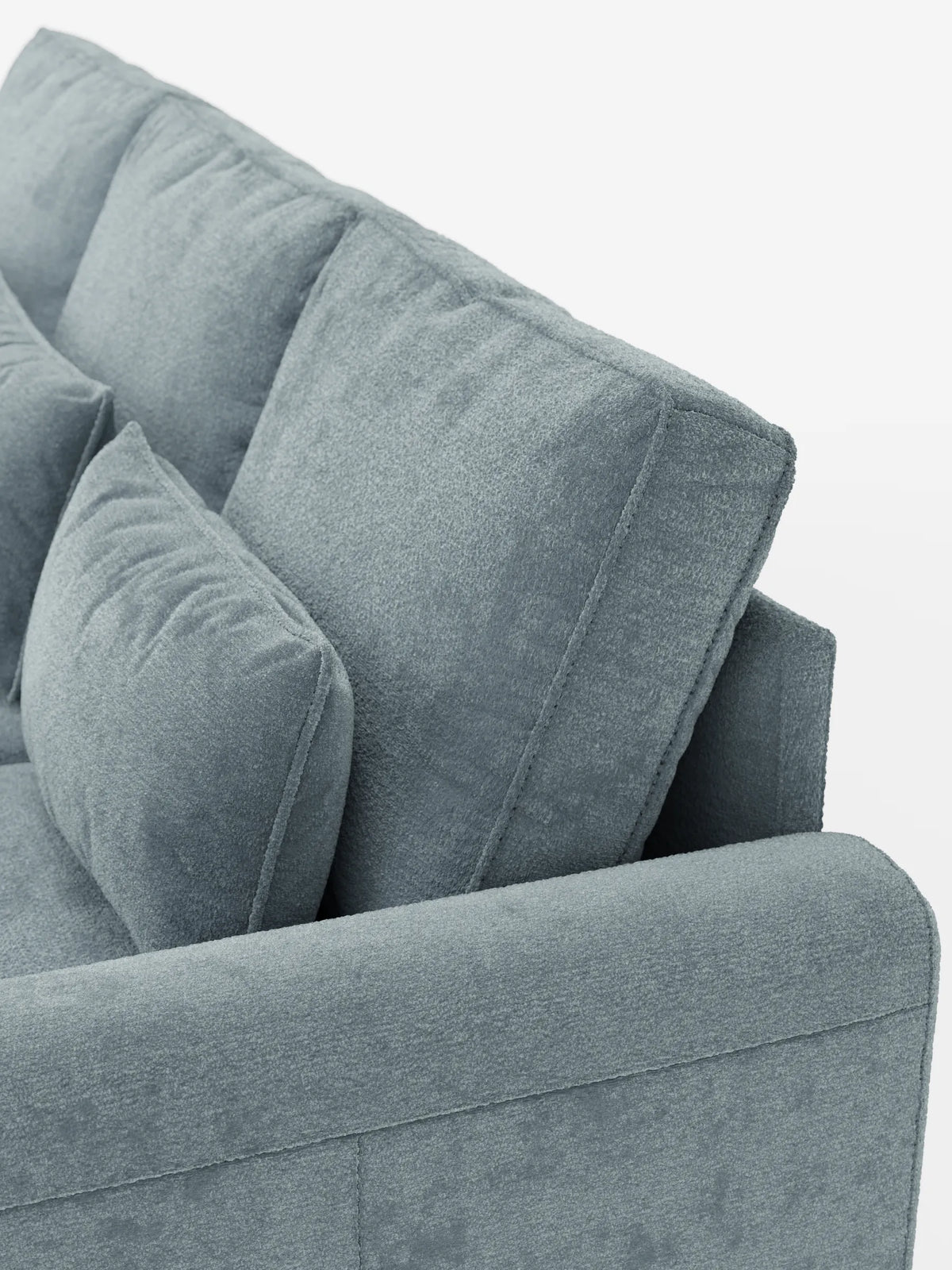 Un primo piano di un divano letto Ottaviano azzurro chiaro con struttura testurizzata, dotato di letto estraibile, penisola reversibile e contenitore in tessuto materico smacchiabile, con cuscini dello schienale spessi, un cuscino decorativo e braccioli arrotondati su uno sfondo bianco.