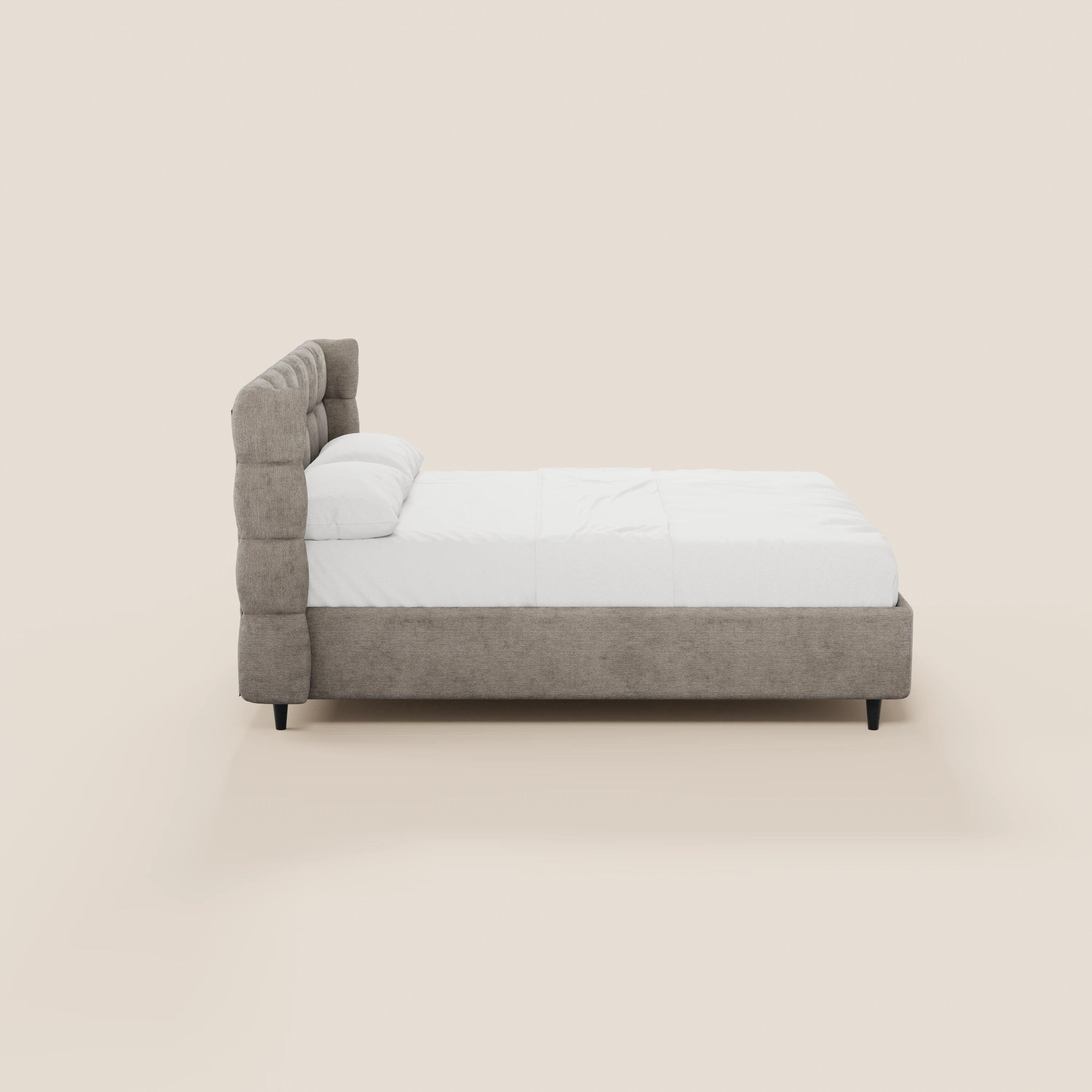 Vista laterale del letto imbottito RAGNAR di Letti.store, caratterizzato da una testiera capitonné avvolgente e da una base contenitore in tessuto grigio chiaro certificato Oeko-Tex®, rifinito con cura con biancheria da letto bianca e due cuscini, su gambe corte scure, su uno sfondo beige chiaro.