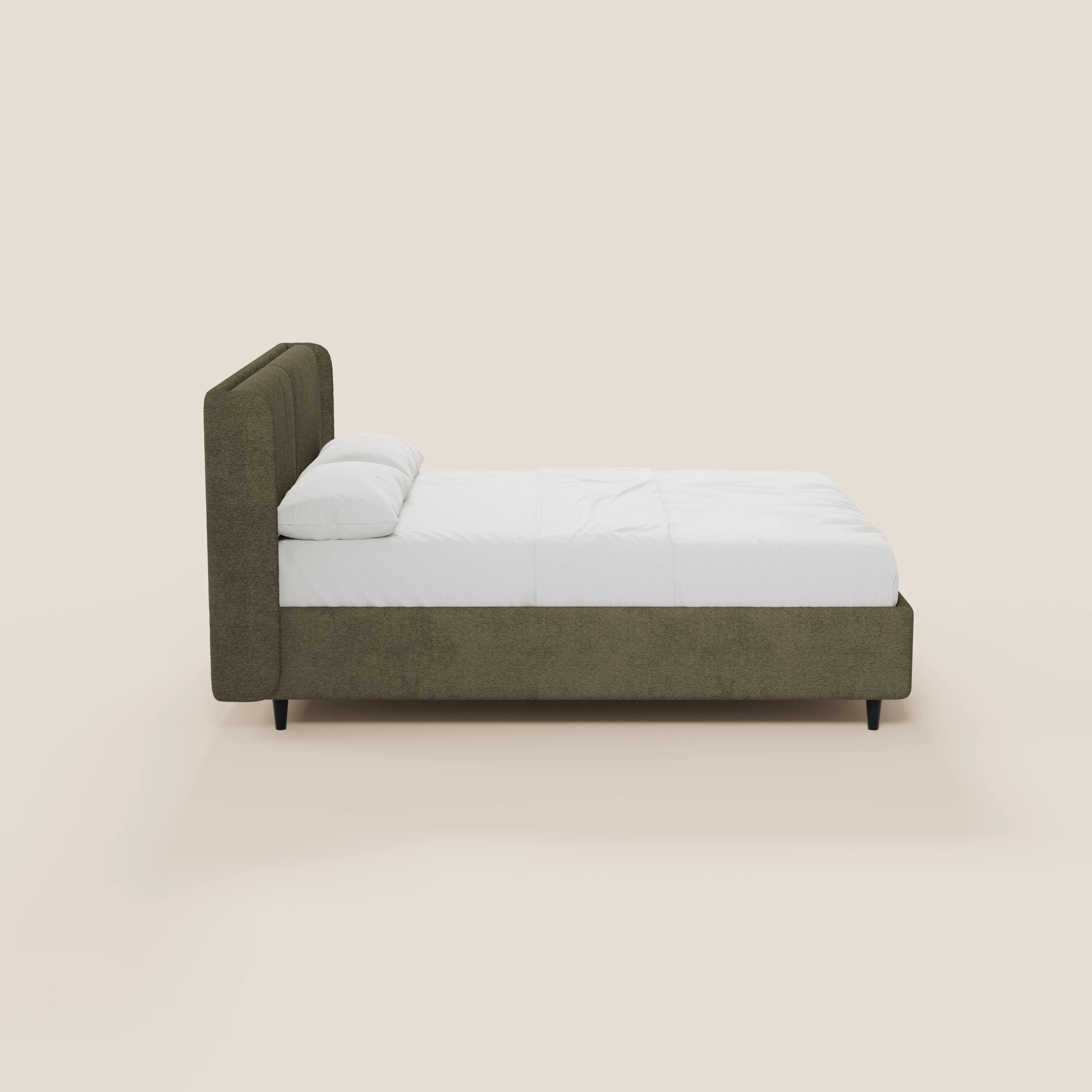 Una vista laterale del letto di design VALKIRIA di Letti.store, caratterizzato da una struttura imbottita in verde oliva certificata Oeko-Tex® e da una testiera avvolgente, biancheria da letto bianca con due cuscini imbottiti, gambe angolate nere, il tutto su uno sfondo beige chiaro.