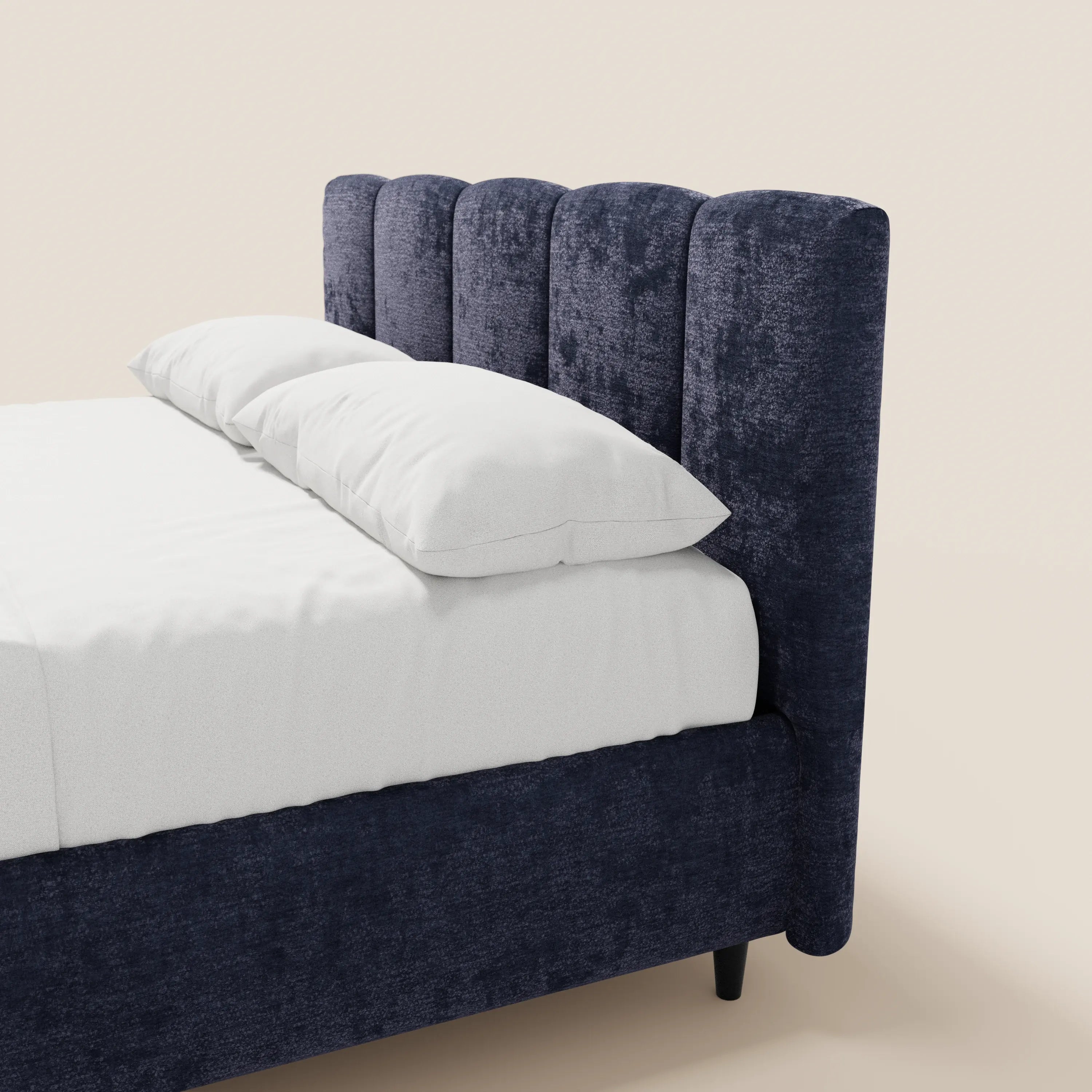 Un primo piano del letto imbottito ARKAM di Letti.store, caratterizzato da un tessuto blu navy certificato Oeko-Tex®, testiera trapuntata a canali verticali, base contenitore, lenzuola bianche e due cuscini, il tutto su uno sfondo beige chiaro a tinta unita per uno stile shabby chic.