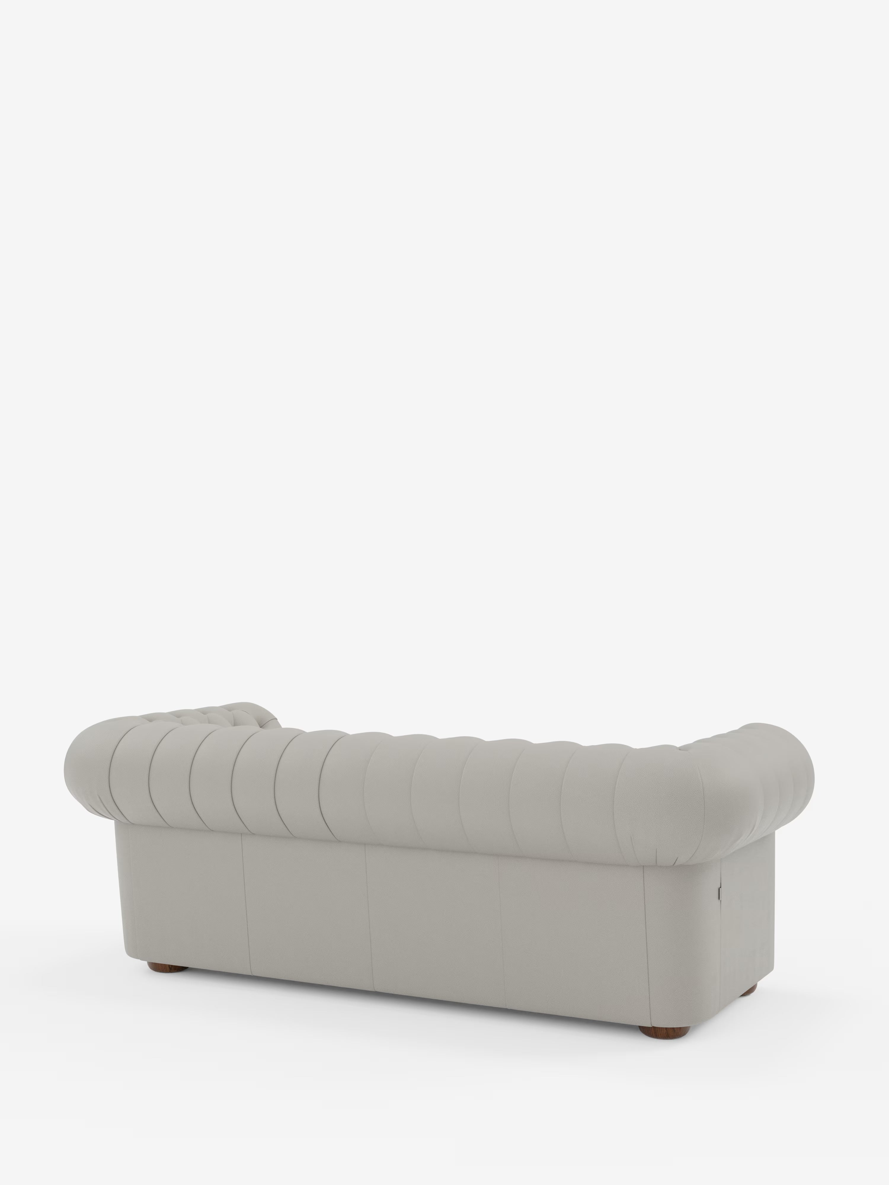 Un divano Chesterfield grigio chiaro con rivestimento a ciuffetti – Divano Chesterfield in vera pelle spessorata a 2 e 3 posti di Divani.Store, caratterizzato da braccioli e schienale arrotondati, è ripreso di retro in un'inquadratura obliqua. Il divano poggia su piccoli piedini in legno davanti a uno sfondo bianco a tinta unita.