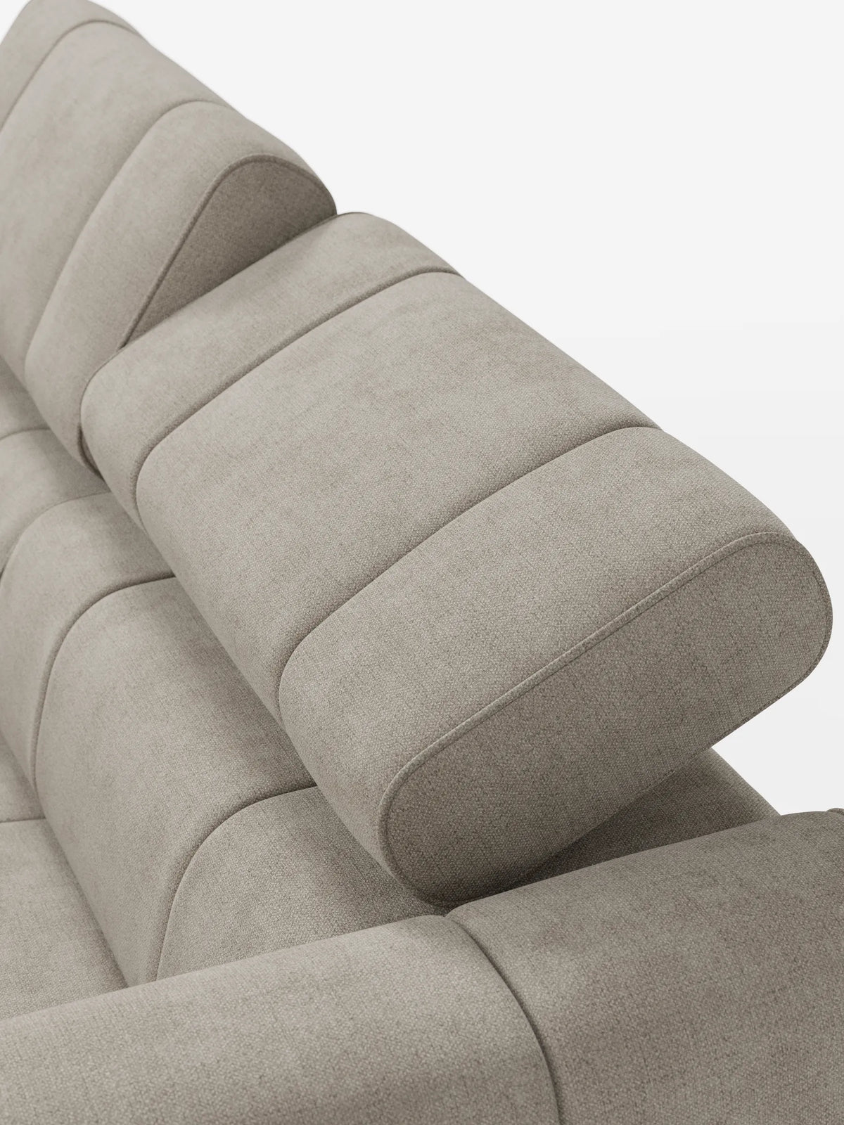 Un primo piano di un divano modulare Giotto a 3 posti color beige con finitura testurizzata, poggiatesta reclinabili e funzione relax elettrica opzionale, rivestito in tessuto smacchiabile T23, caratterizzato da cuscini spessi e segmentati e da poggiatesta arrotondati e regolabili su uno sfondo a tinta unita.