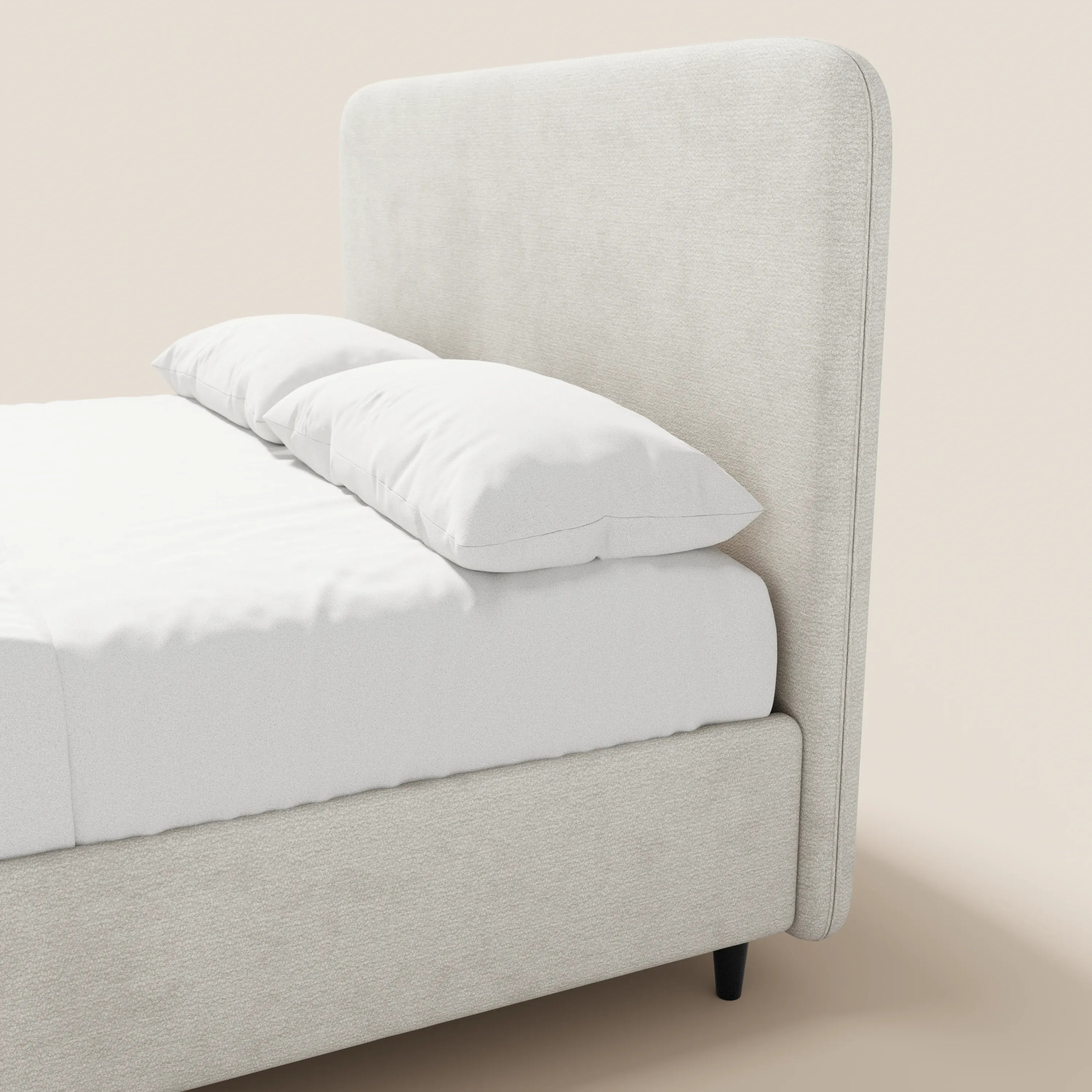 Il letto imbottito KAELOS minimal di Letti.store presenta una testiera alta e arrotondata in ciniglia color beige chiaro, piedini alti e una base contenitiva; è abbinato a lenzuola bianche immacolate e due cuscini su uno sfondo a tinta unita.