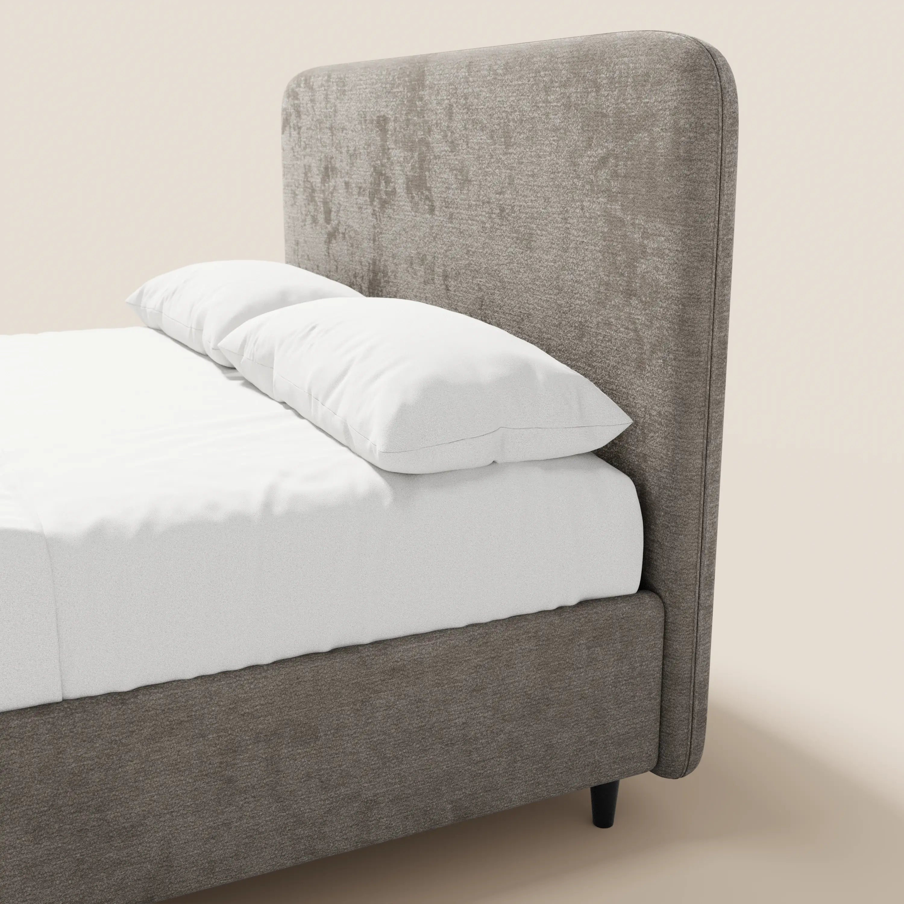 Il letto imbottito KAELOS minimal di Letti.store presenta una testiera alta e ricurva in ciniglia, un tessuto testurizzato grigio chiaro, gambe alte nere e un vano contenitore. È esposto ben rifatto, con biancheria da letto bianca su uno sfondo beige chiaro.