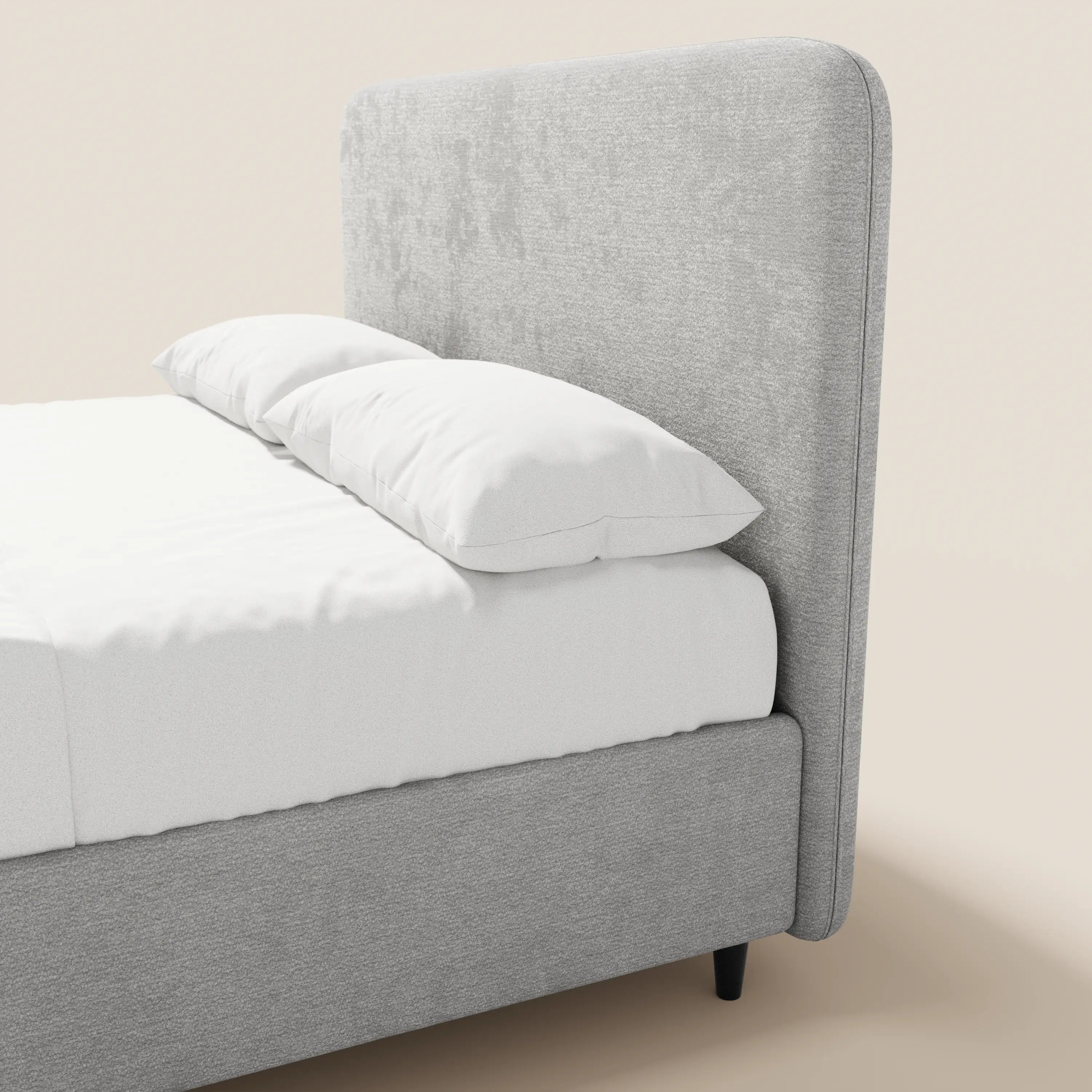 Il letto imbottito KAELOS minimal di Letti.store presenta una testiera alta e arrotondata in ciniglia e gambe alte, con una struttura imbottita abbinata in grigio chiaro. La biancheria da letto e i cuscini bianchi completano il suo look pulito su uno sfondo beige neutro.