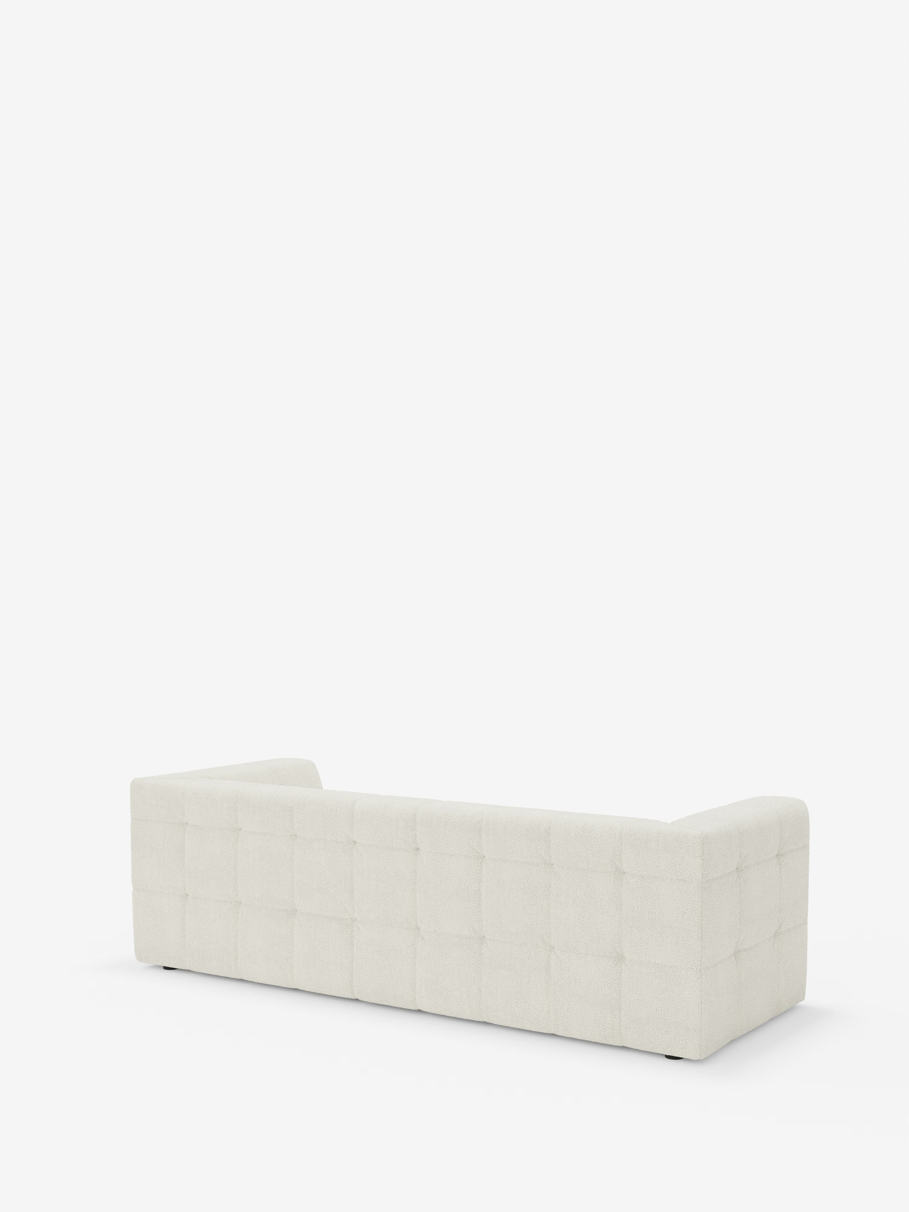 Il divano modulare Mosaic a 3 e 4 posti in bouclé di Divani.Store è raffigurato nella vista posteriore, con rivestimento in tessuto T21 bianco sporco, resistente alle macchie, caratterizzato da un motivo a griglia quadrata capitonné (imbottito). La silhouette moderna e dal profilo basso presenta braccioli alla stessa altezza dello schienale, che risaltano su uno sfondo bianco a tinta unita.